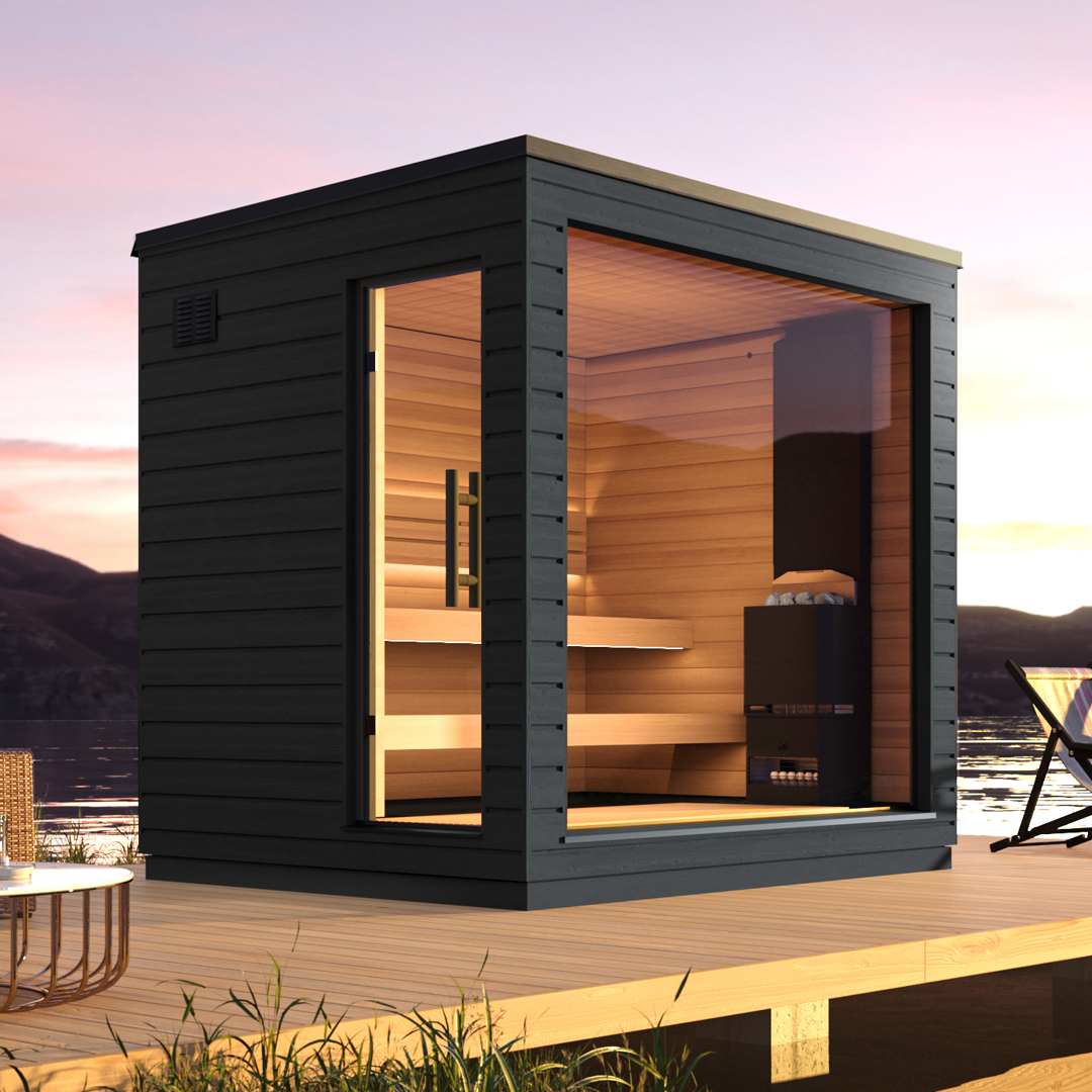 An outdoor sauna with floor-to-ceiling windows, constructed from wood with a black exterior and clear glass, set in a scenic location with bodies of water and a sunset in the background.