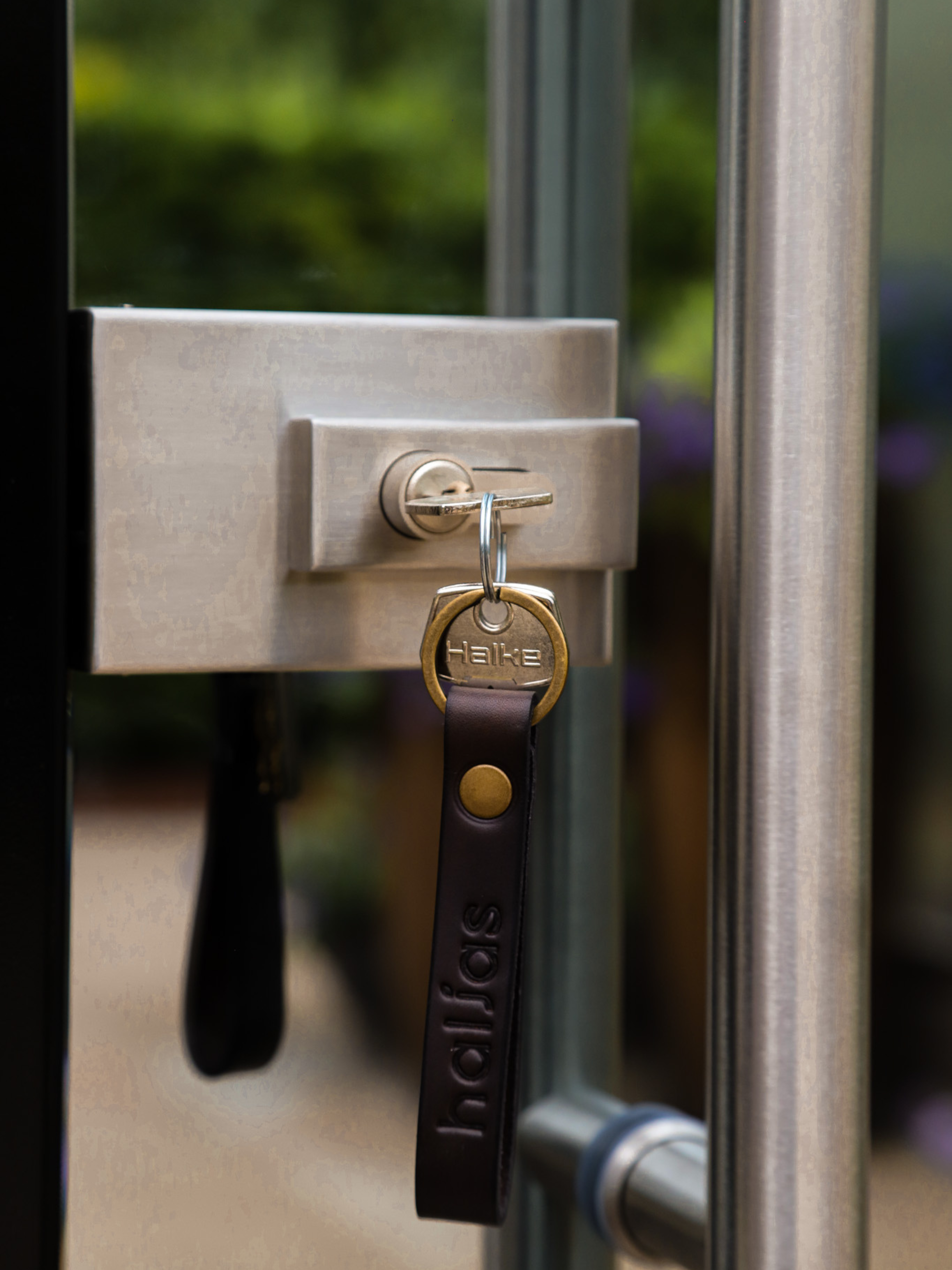 Lock on a glass door with a key inserted, featuring the brand 'Hafele'.