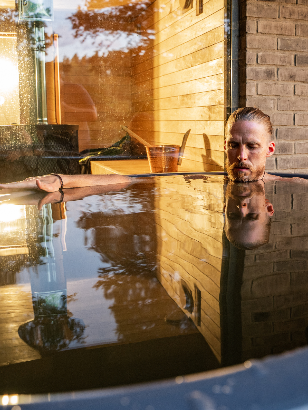 Man sitting in a hot tub with a wooden cabin exterior