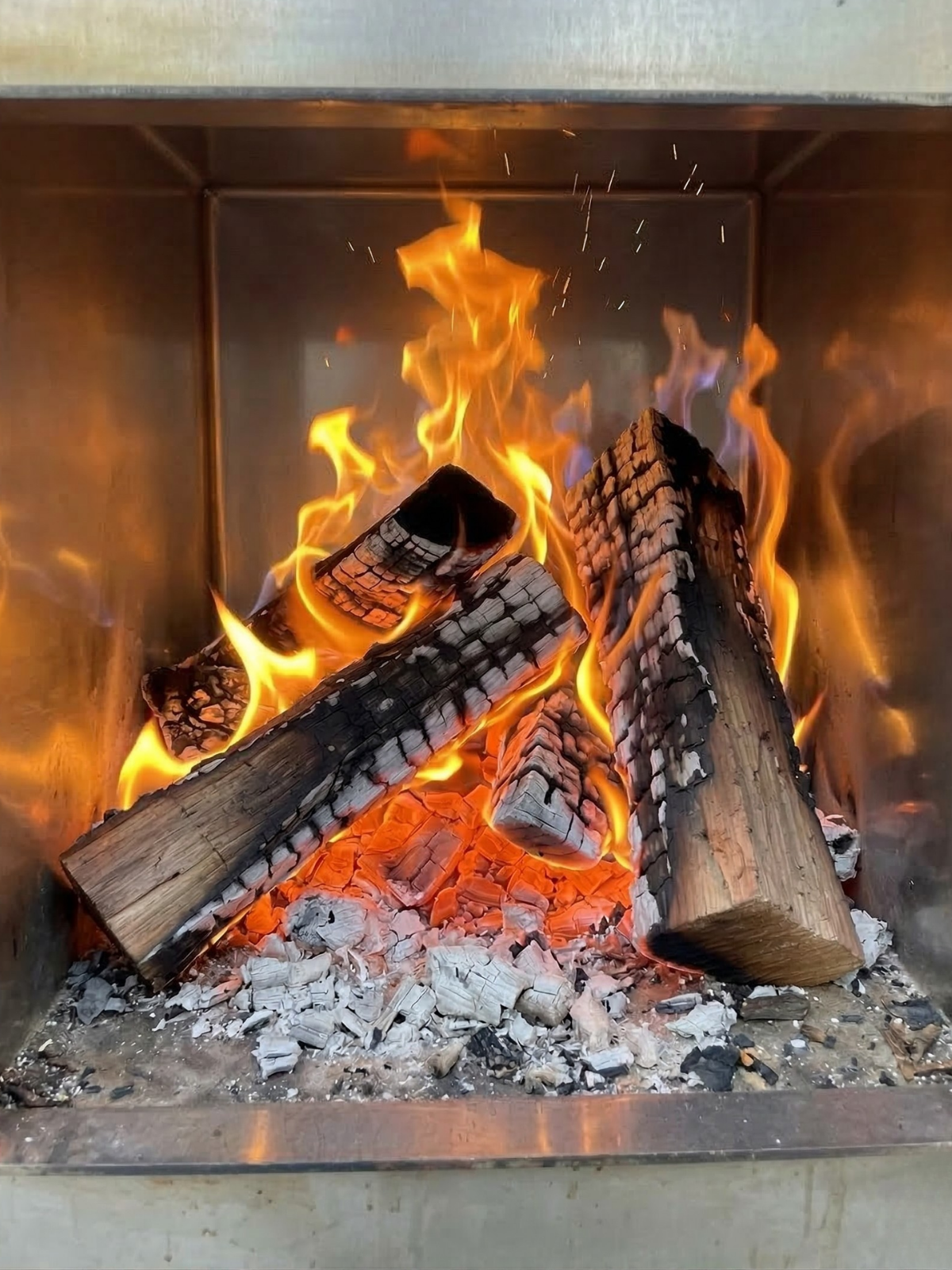 Wood logs burning in a fireplace with flames and embers.