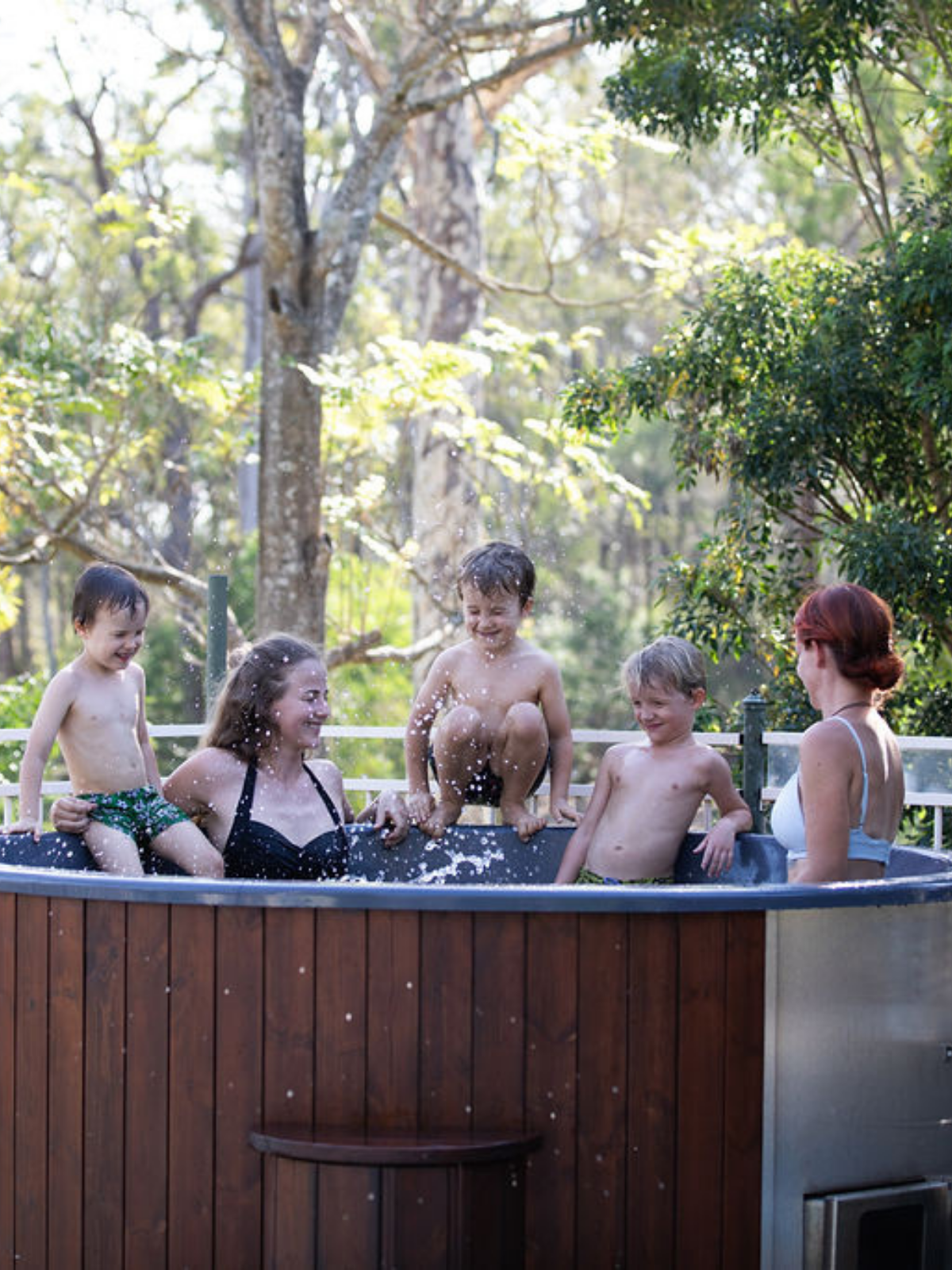 Family enjoying a hot tub outdoors with trees in the background