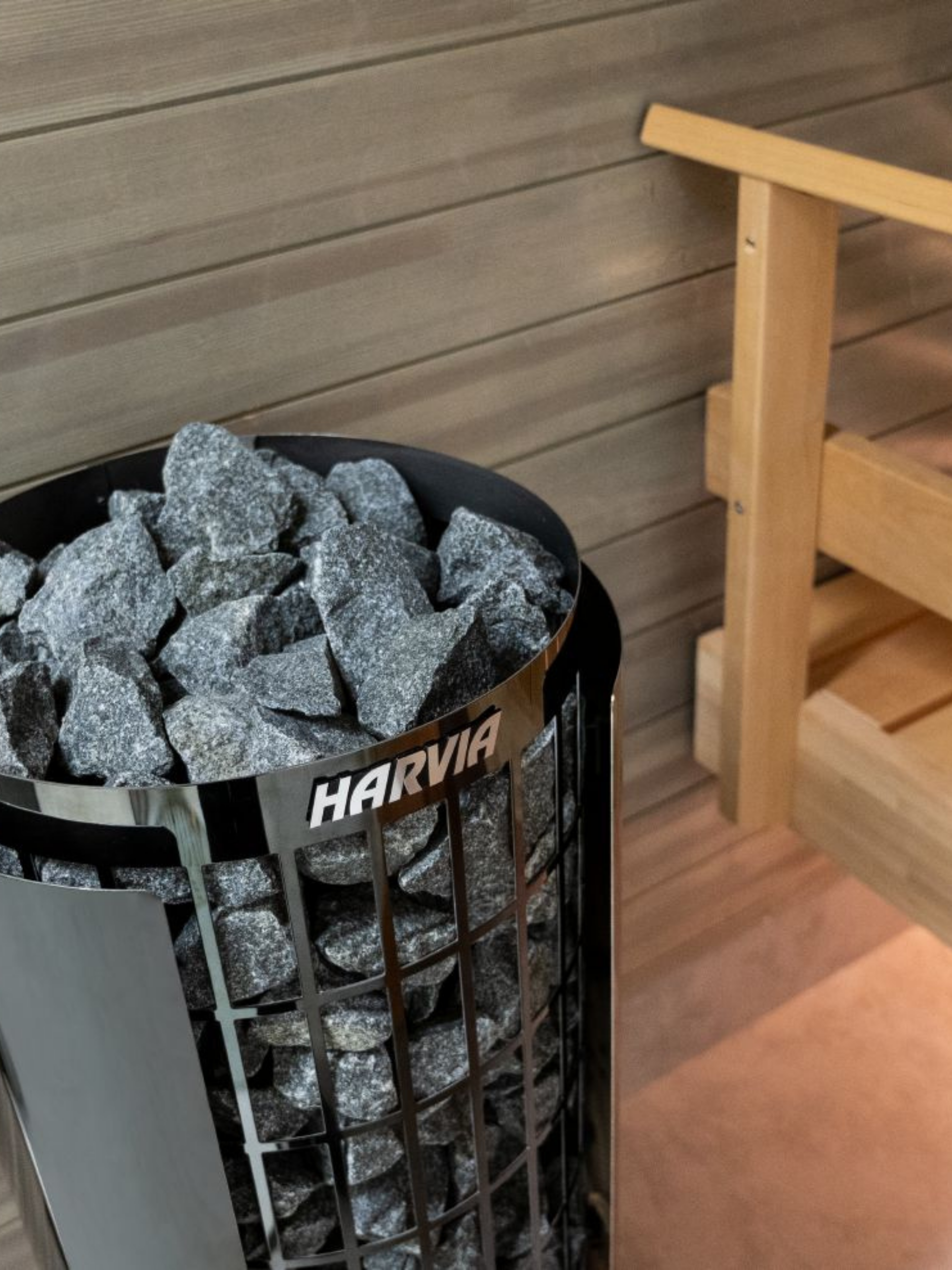 Harvia sauna stone container with stones inside, placed against a wooden sauna wall.