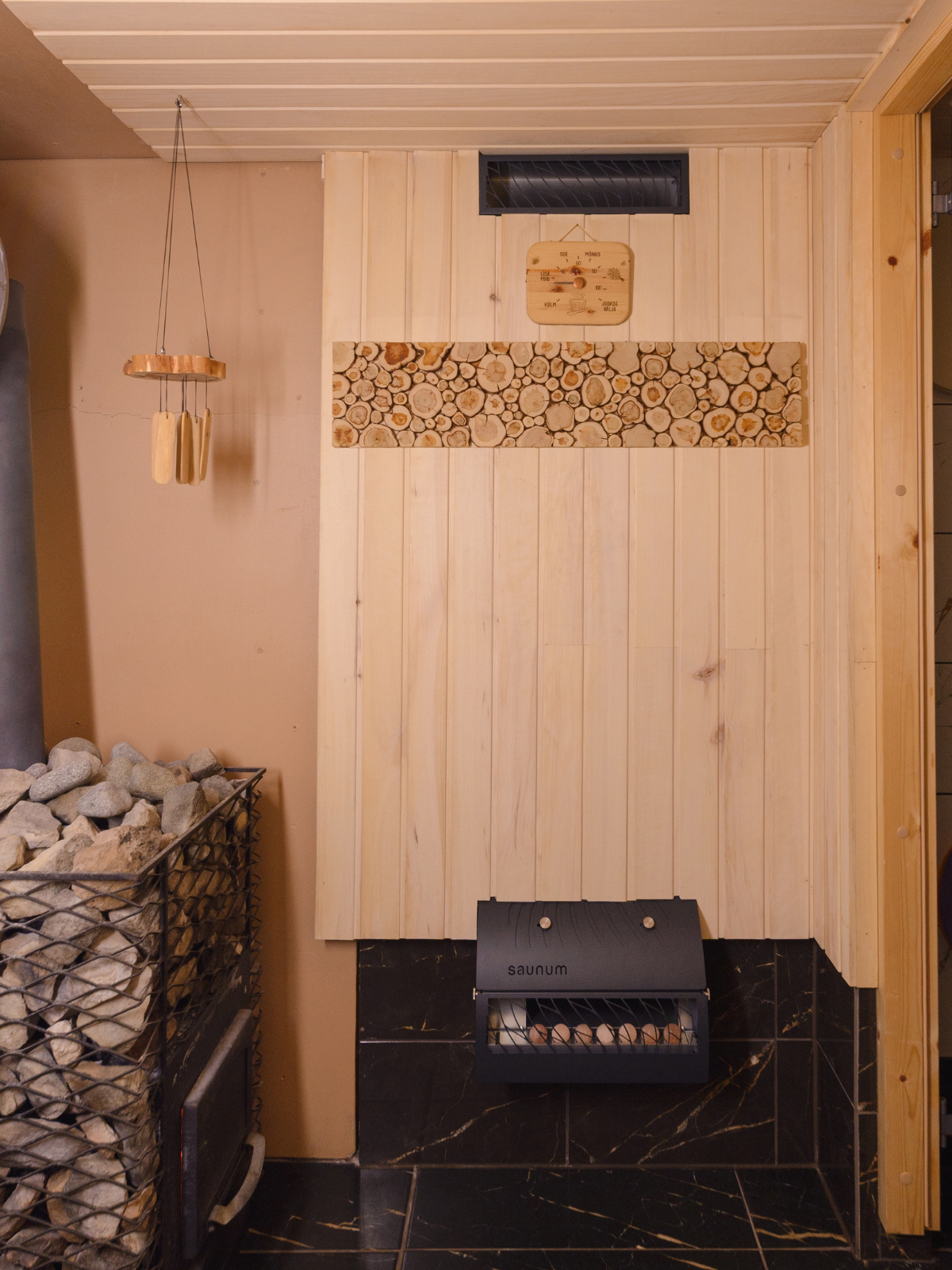 Sauna interior with wooden walls, black floor, and a small stove.
