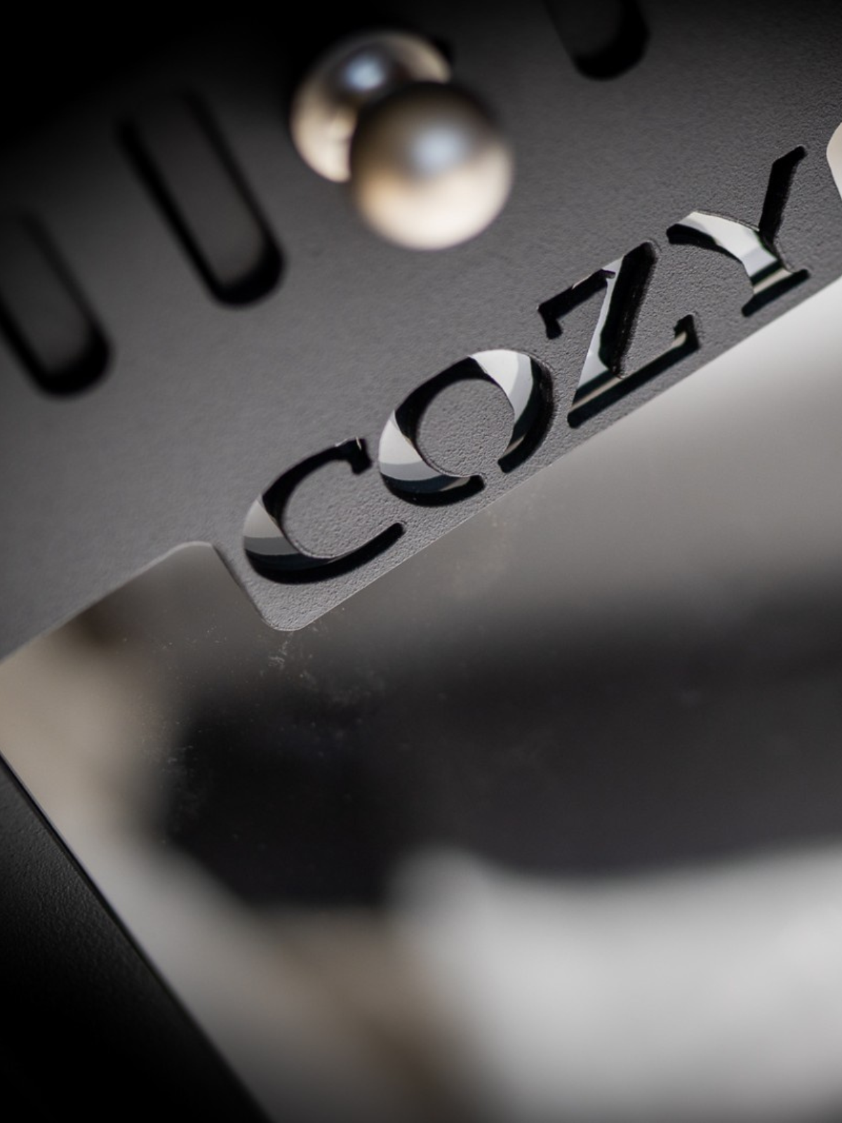 Close-up of a metallic surface with 'COZY' branding.