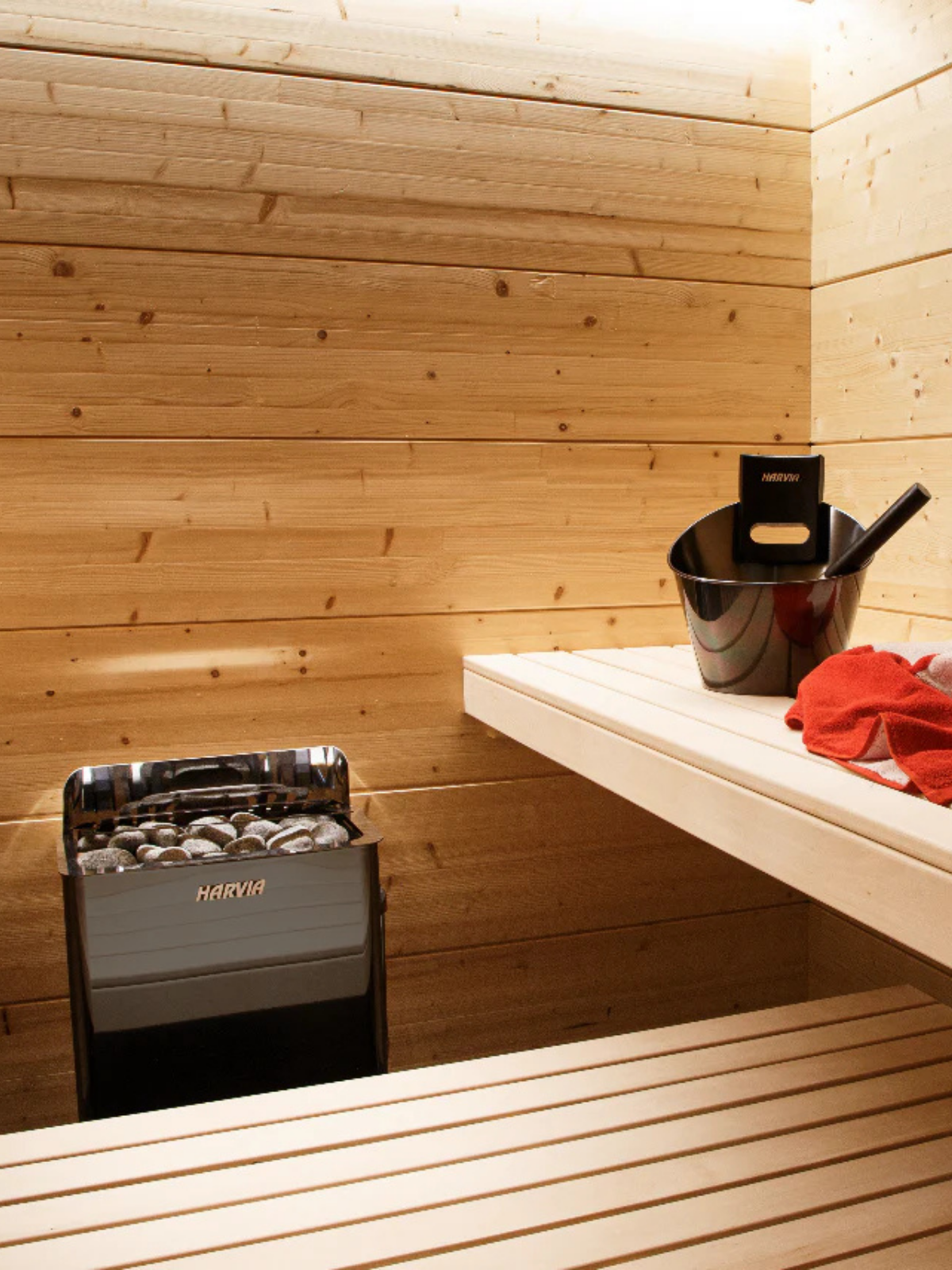 Wooden sauna interior with a heater and a shelf.