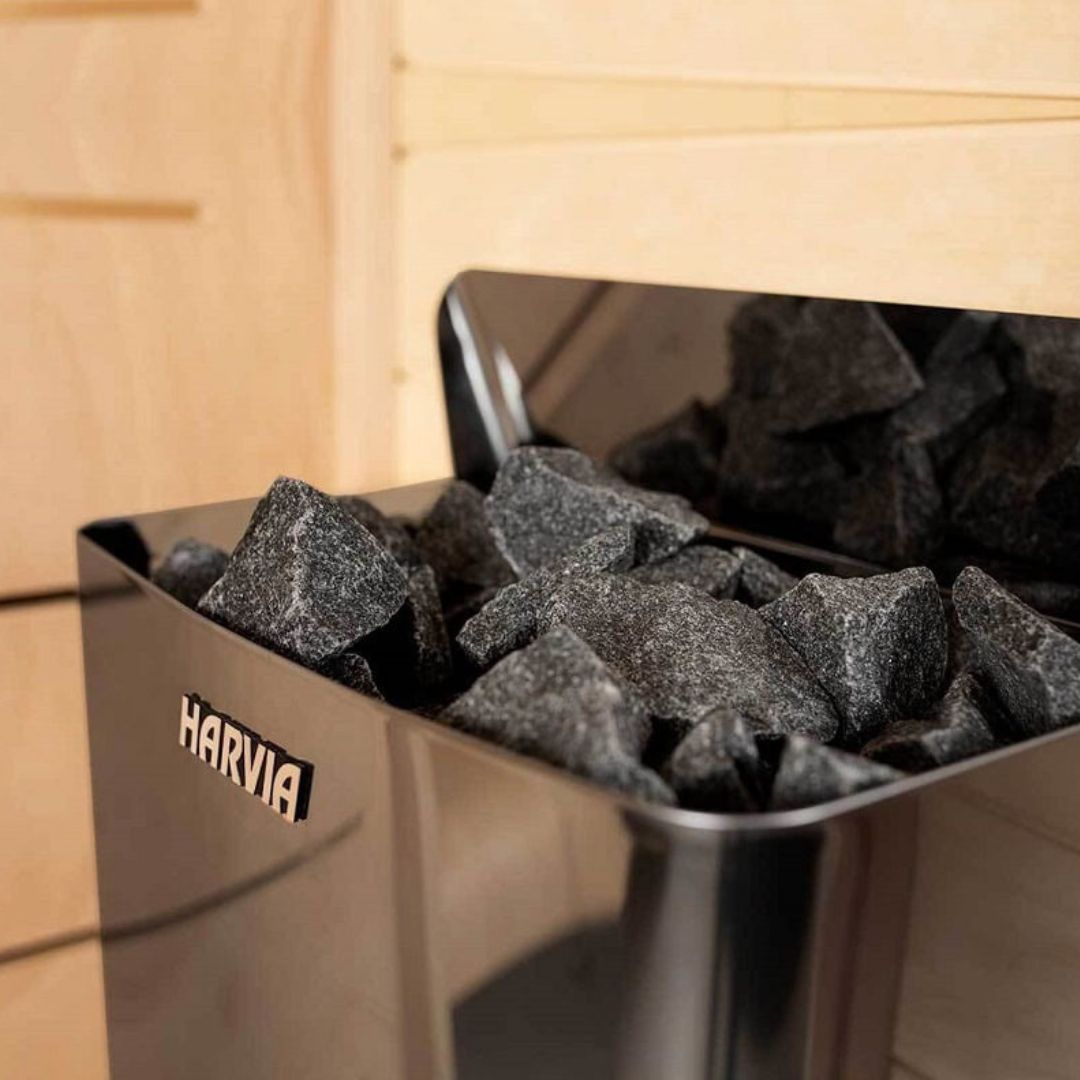 A Harvia sauna heater filled with sauna rocks, featuring illuminated control switches and a compact design.