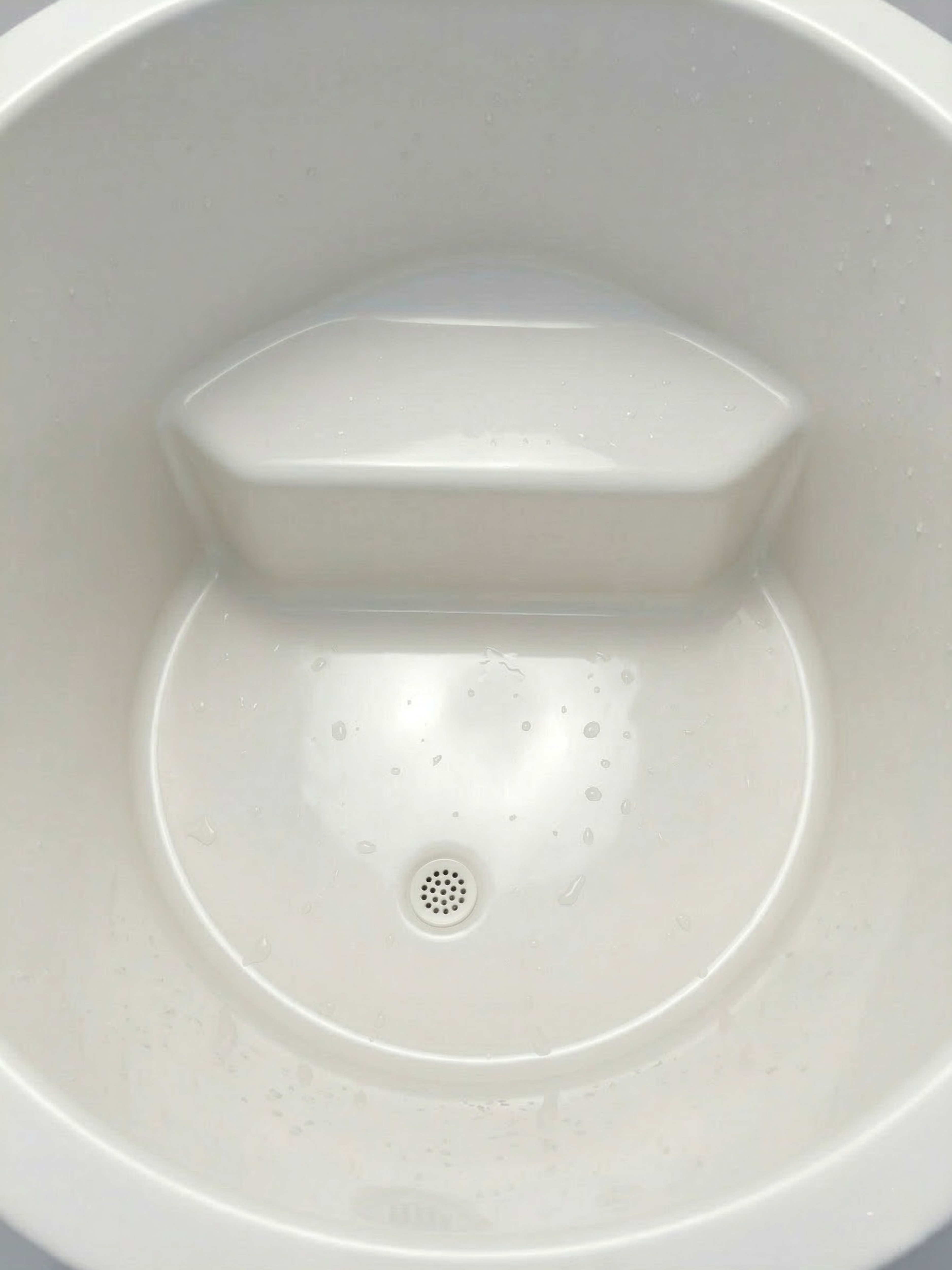 White plastic component with hexagonal top and circular base on a white background