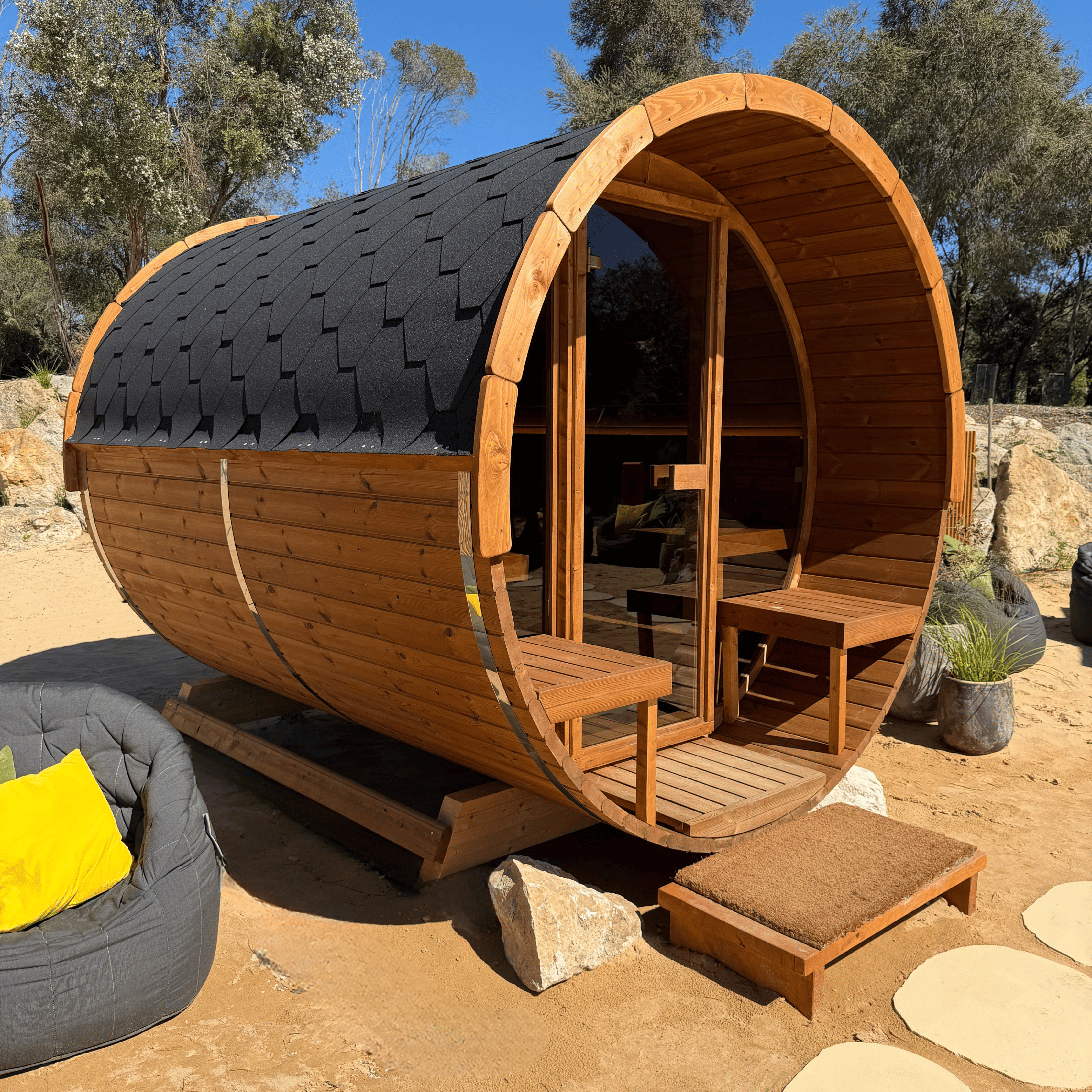 Wooden barrel-shaped cabin with seating area in a natural setting