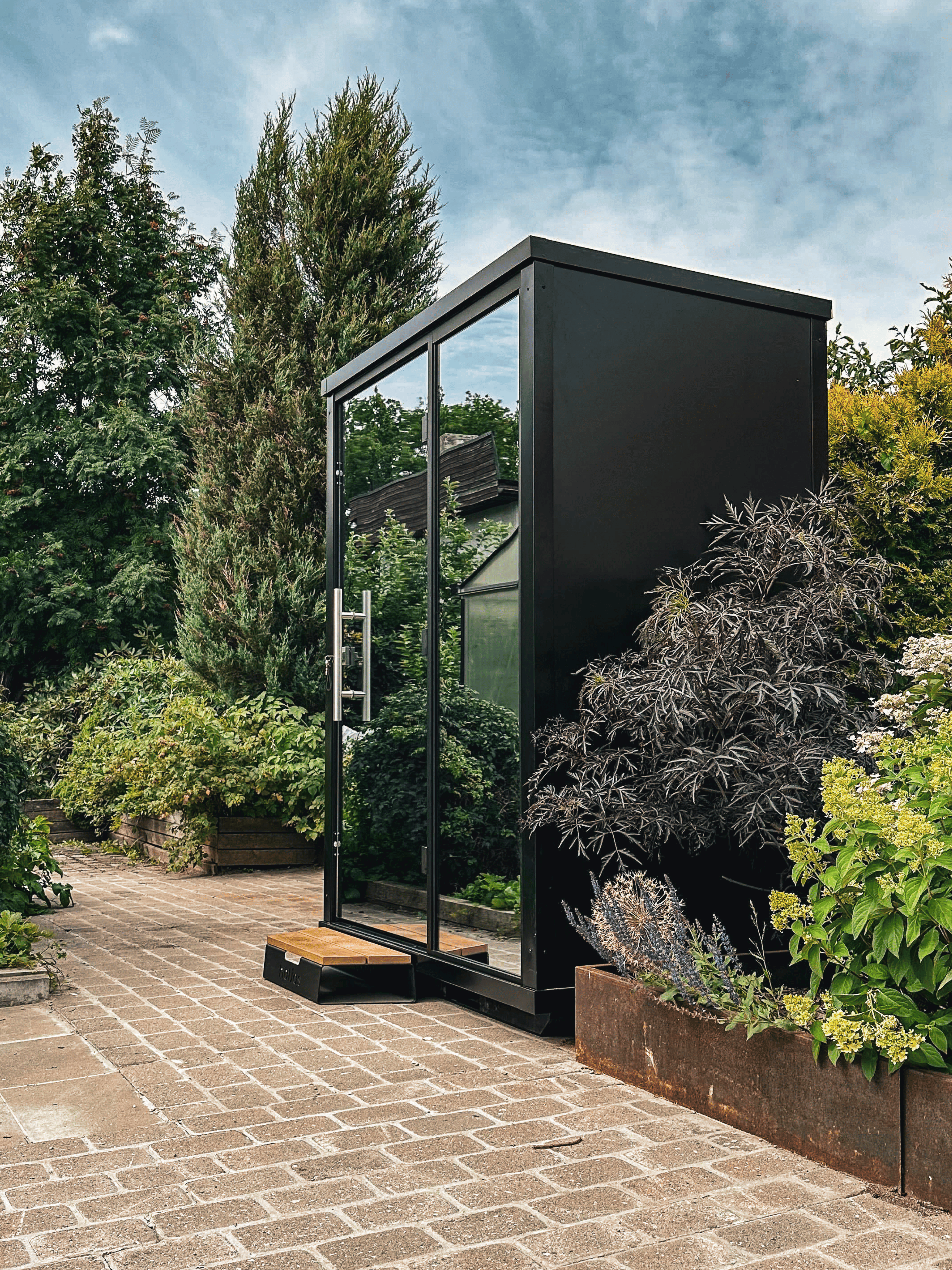 Modern black garden shed with glass doors in a garden setting