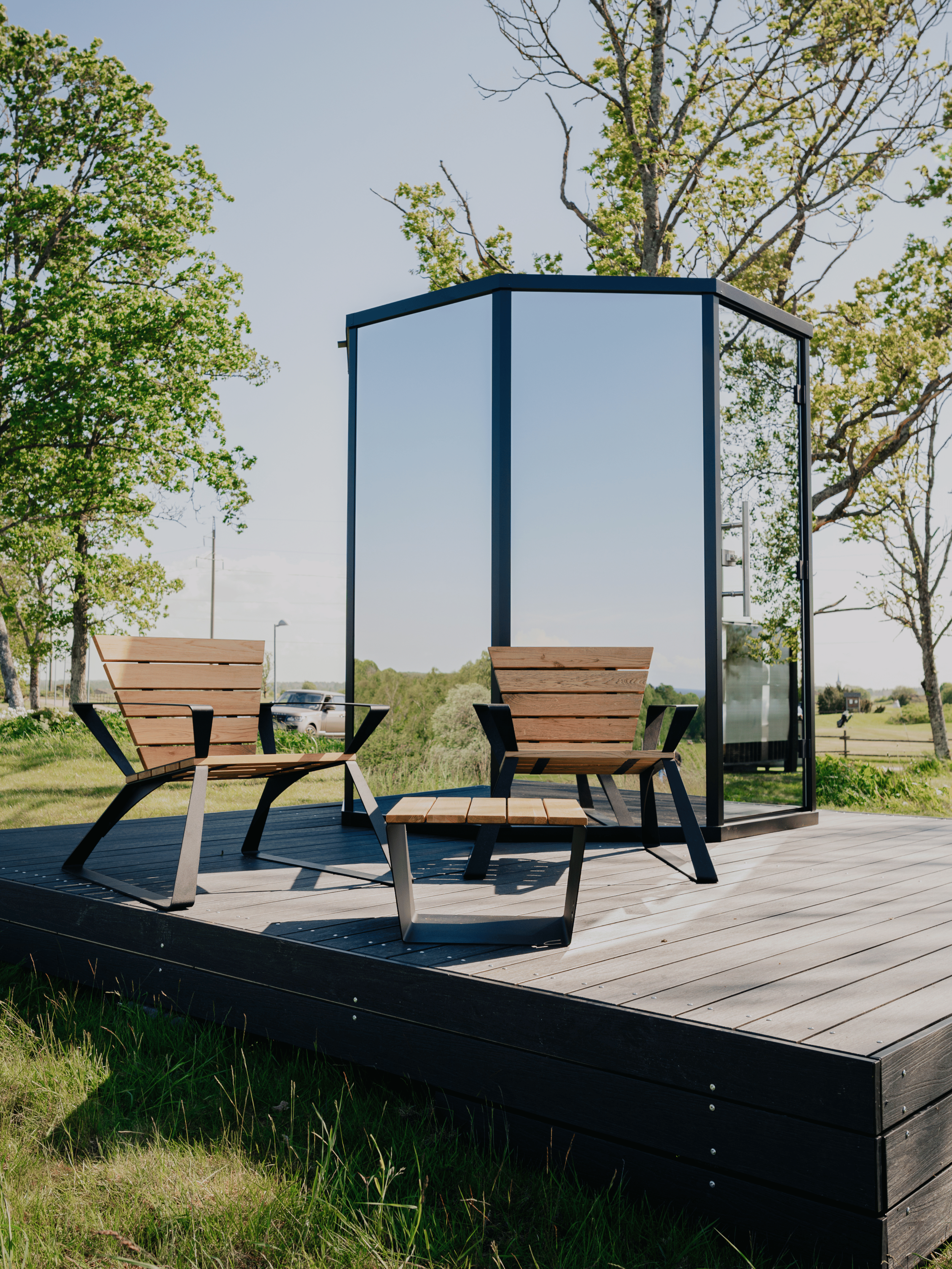 Outdoor patio with wooden chairs and a glass enclosure on a wooden deck.