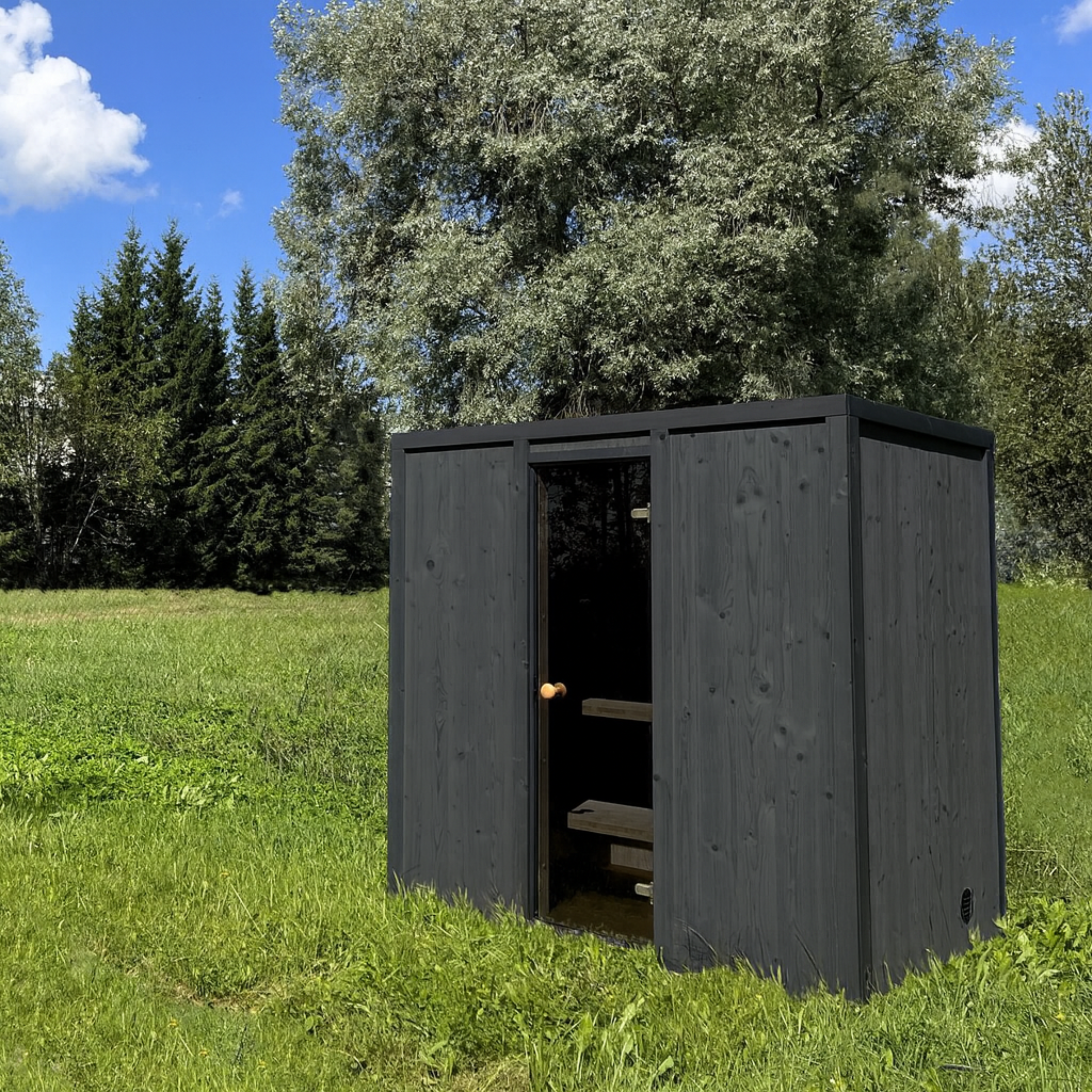 Wooden shed in a grassy area with trees in the background