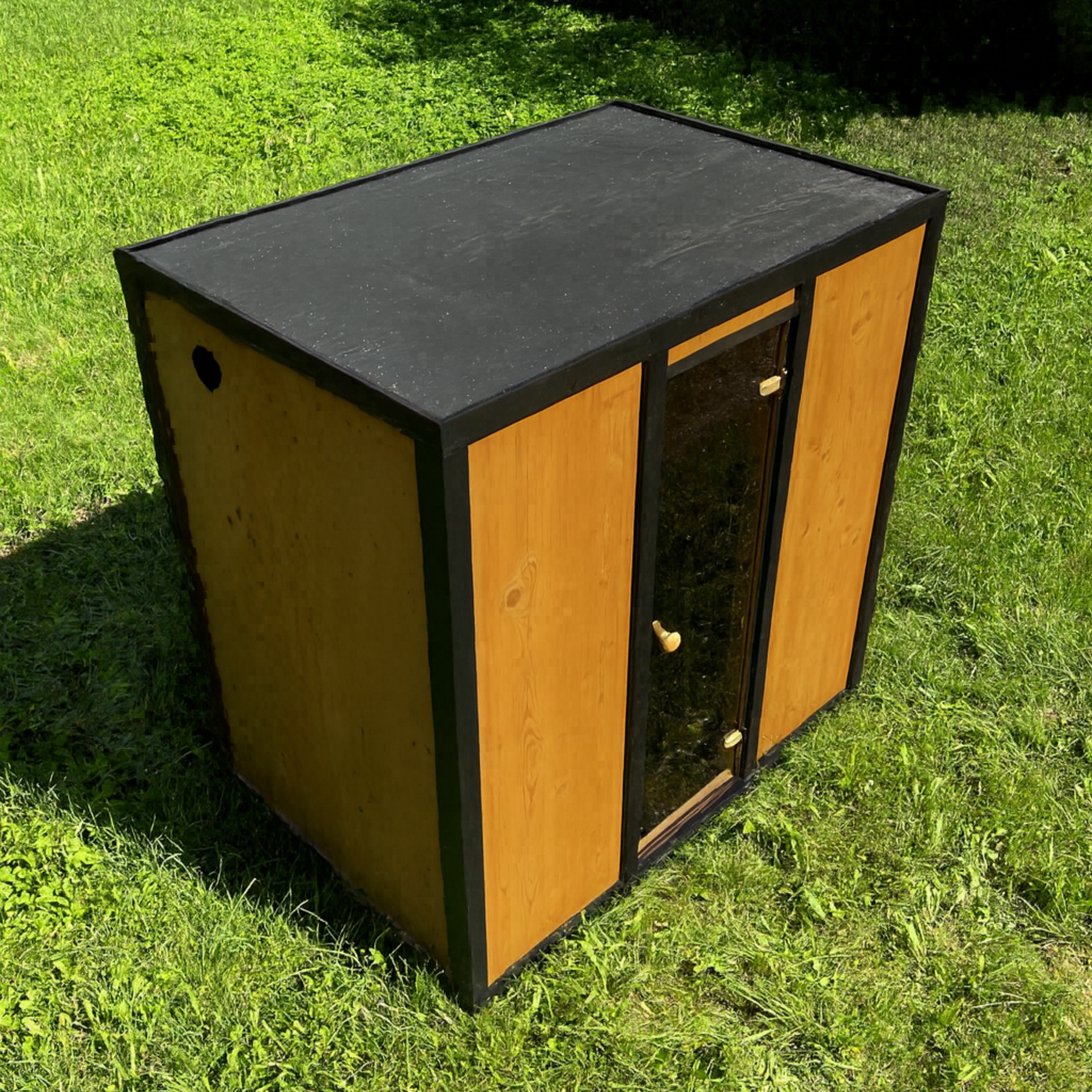Wooden pet house with a black roof on grass