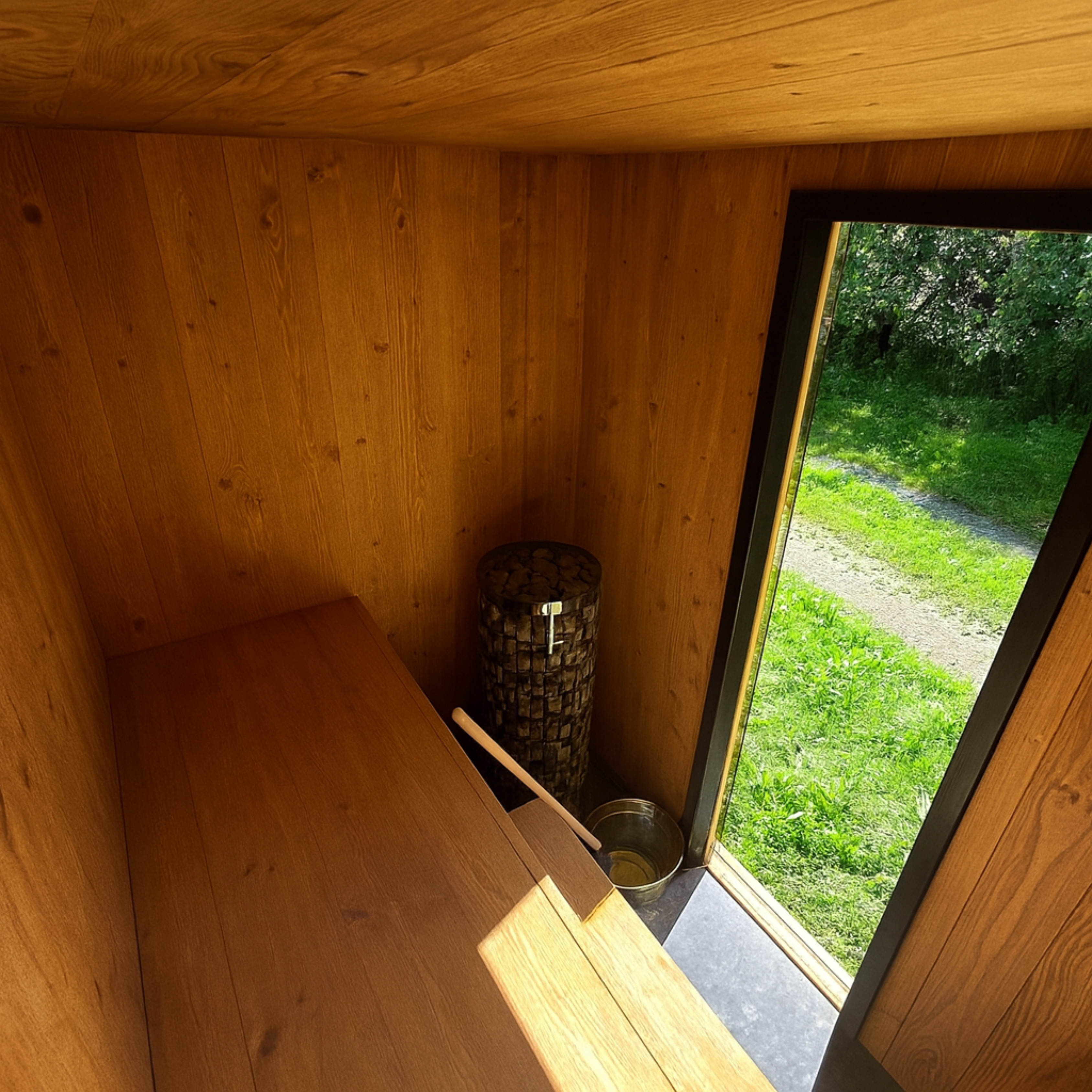 Wooden interior of a cabin with a window showing greenery outside