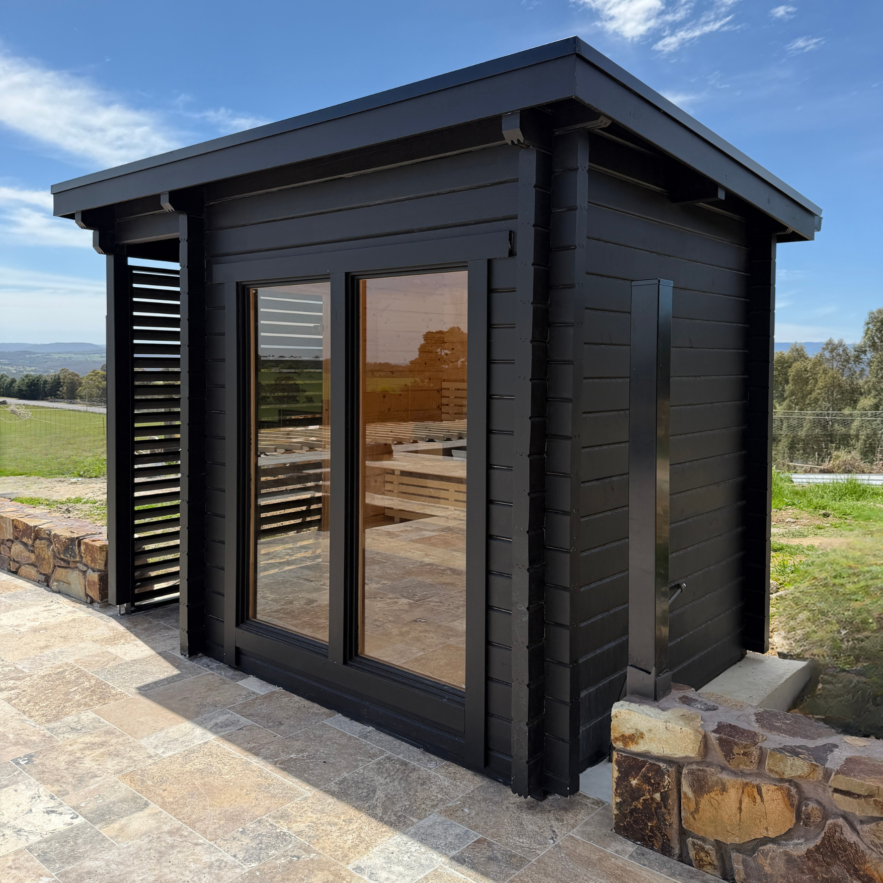 Black wooden shed with glass doors in a garden setting
