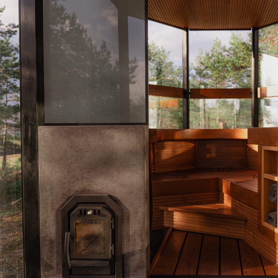 Wooden sauna with a stone wall and large windows overlooking trees