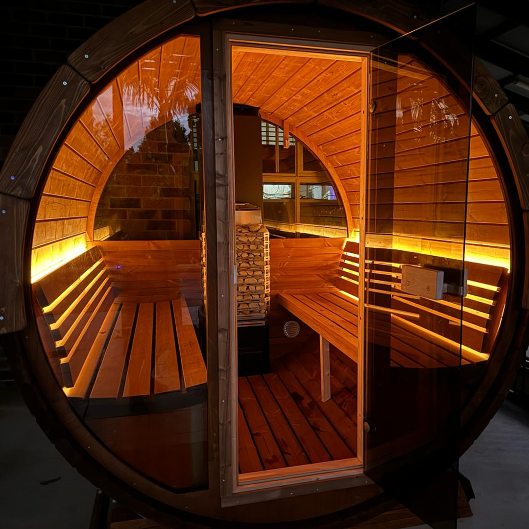 A cozy, barrel-shaped sauna with warm, glowing lights illuminating its wooden interior. Benches line the walls, creating an inviting, relaxing ambiance.