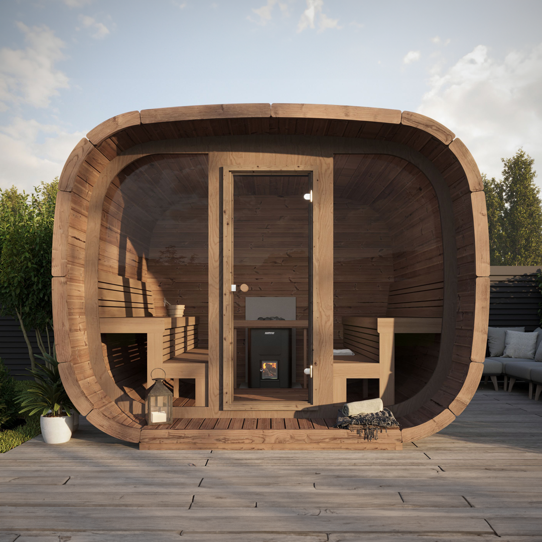 Modern outdoor wooden sauna with a curved design, glass door, and wooden benches inside. It sits on a wooden deck with plants and patio furniture nearby.