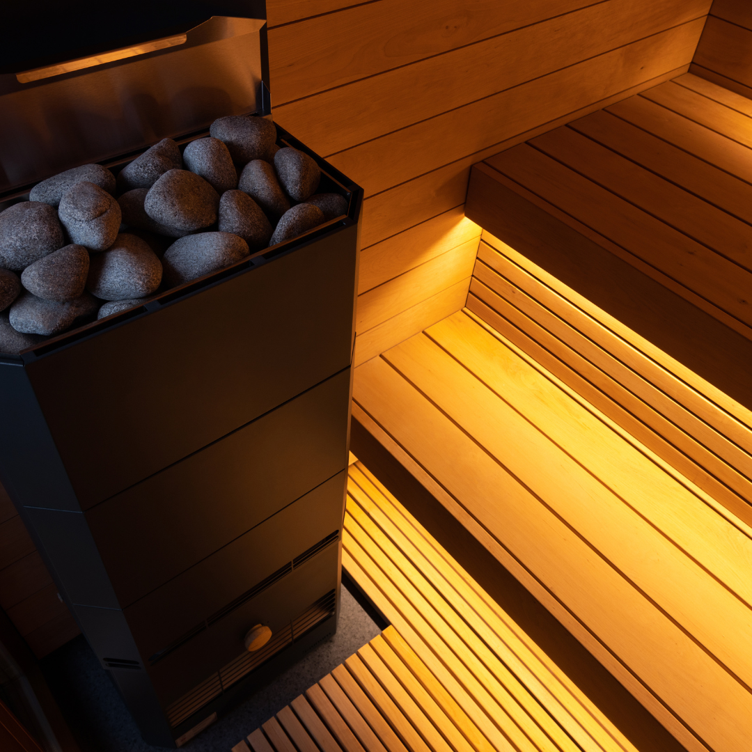 Wooden sauna with rocks inside a container, illuminated by warm light.