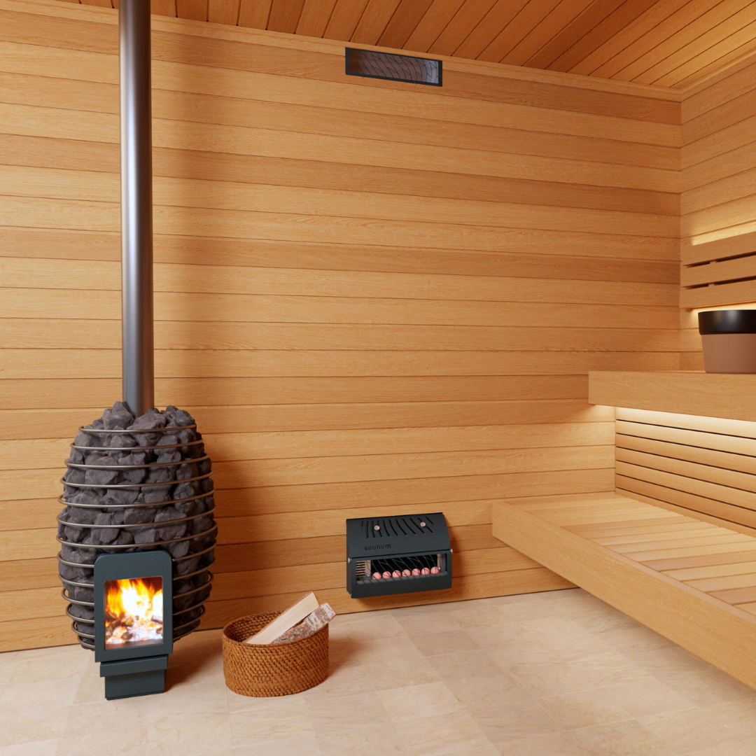 A cozy sauna with light wood paneling, a stove with visible flames, a basket of firewood, and tiered seating, creating a warm, relaxing atmosphere.