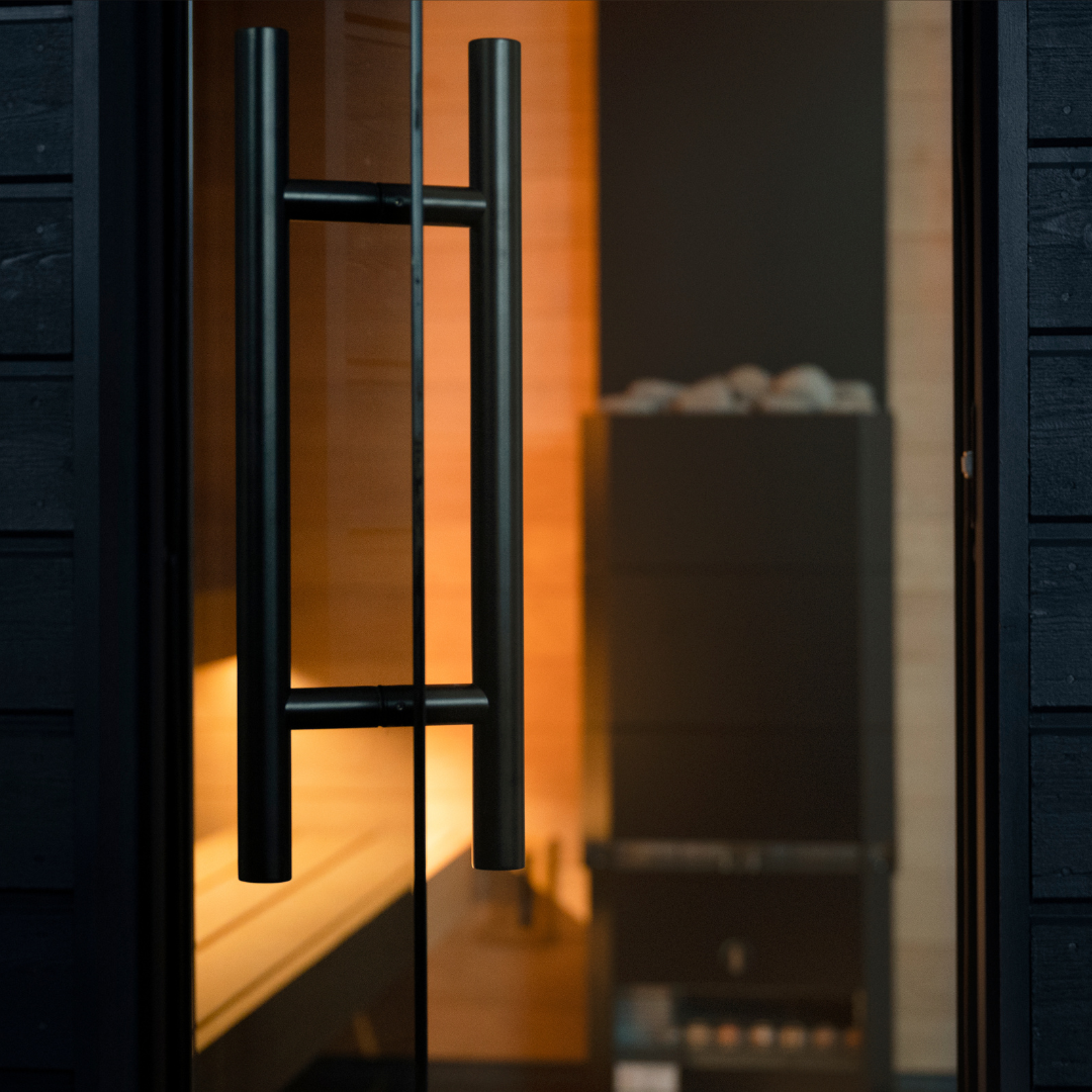 Close-up of a glass door with black metal handles, blurred interior background