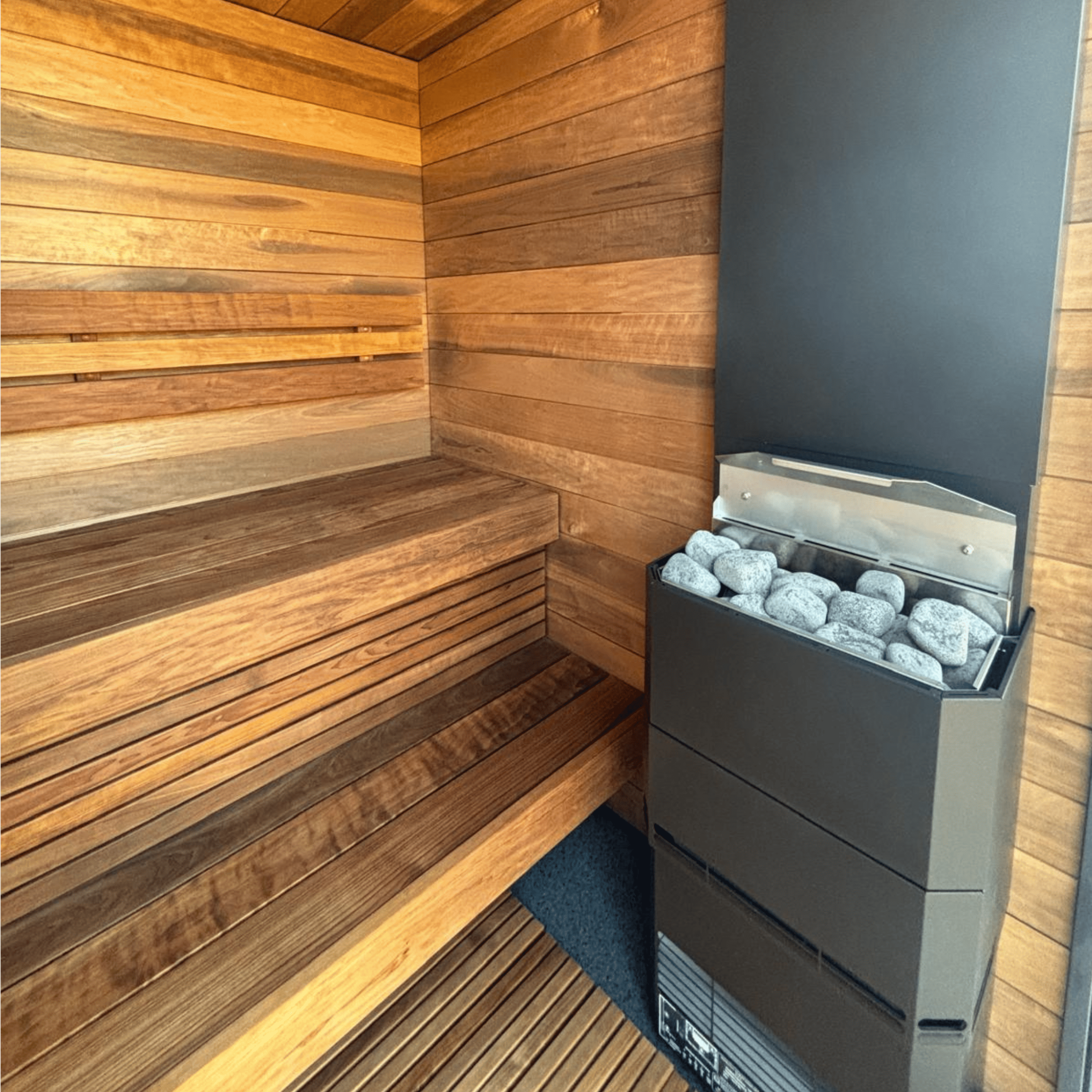 Sauna interior with wooden walls and a black sauna heater.