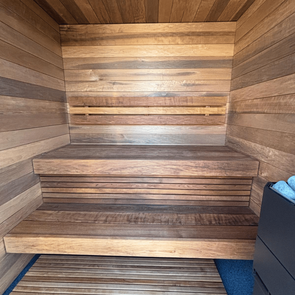 Wooden sauna with benches and a blue mat on the floor