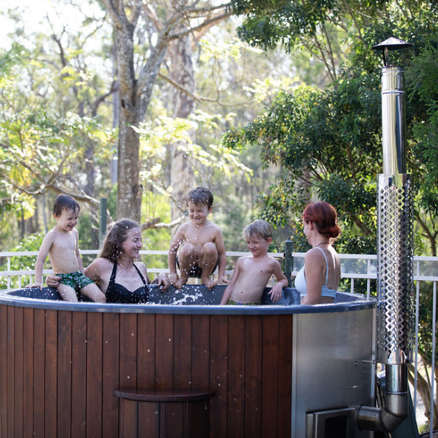 Children playing in a hot tub outdoors with trees in the background