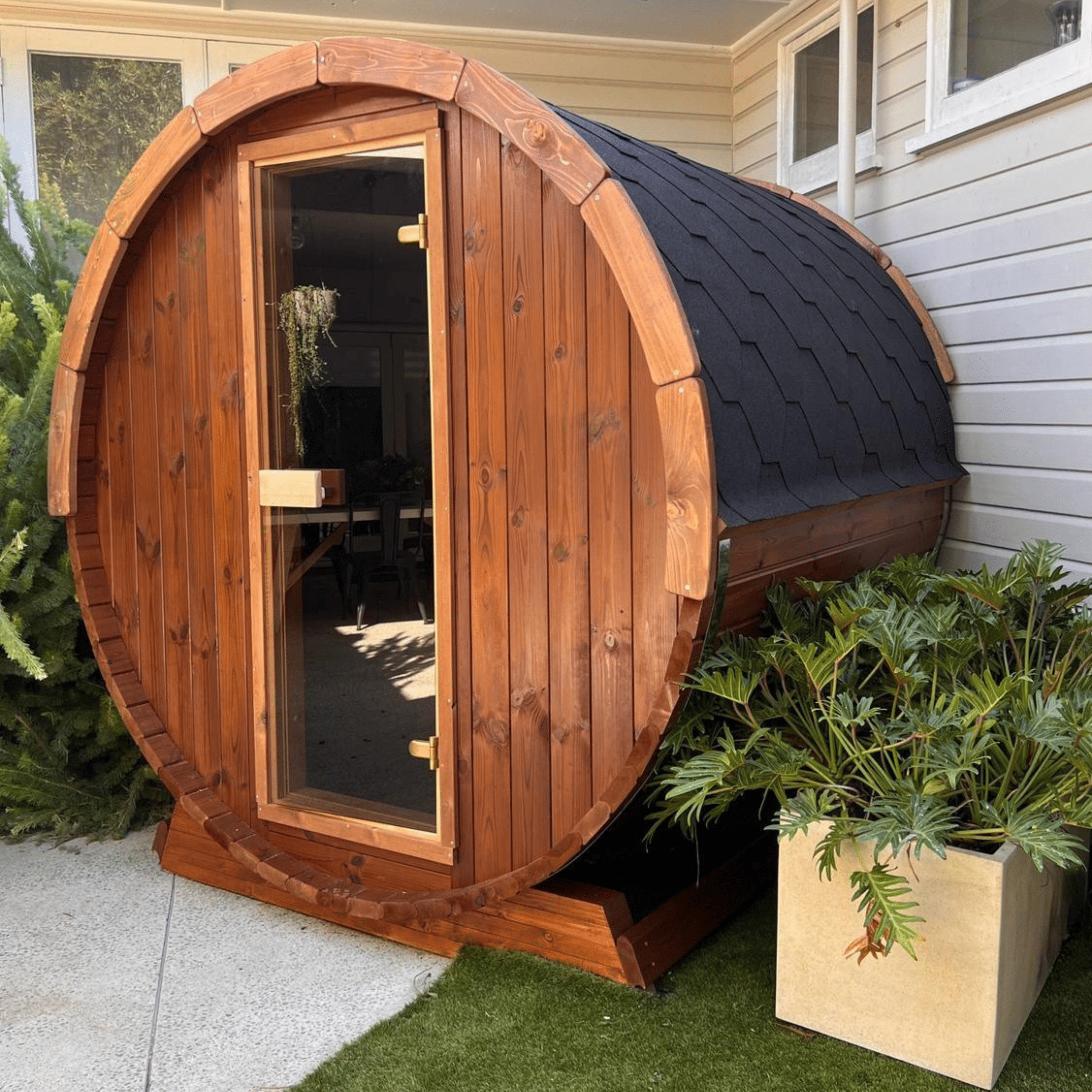 Wooden barrel-shaped structure with a black roof in an outdoor setting.