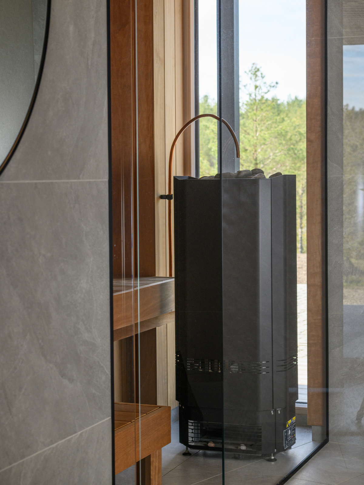 Black cylindrical object against a glass wall with a view of greenery