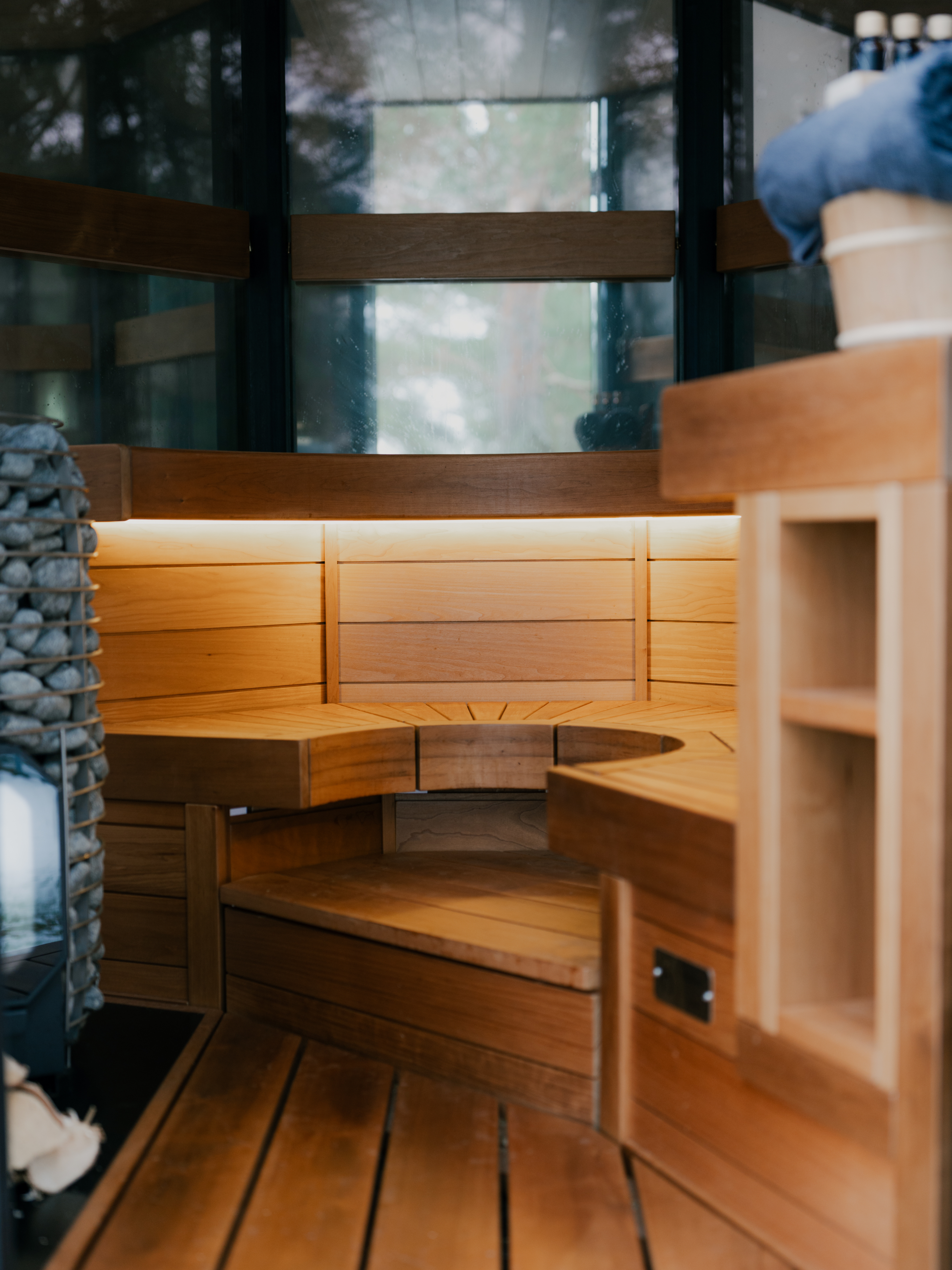 Wooden sauna interior with a stone wall and wooden bench.