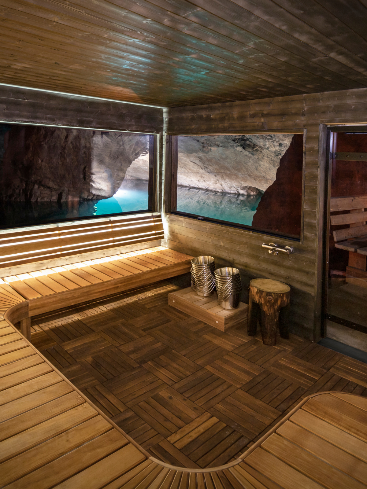 Wooden sauna interior with large windows showing natural scenery.