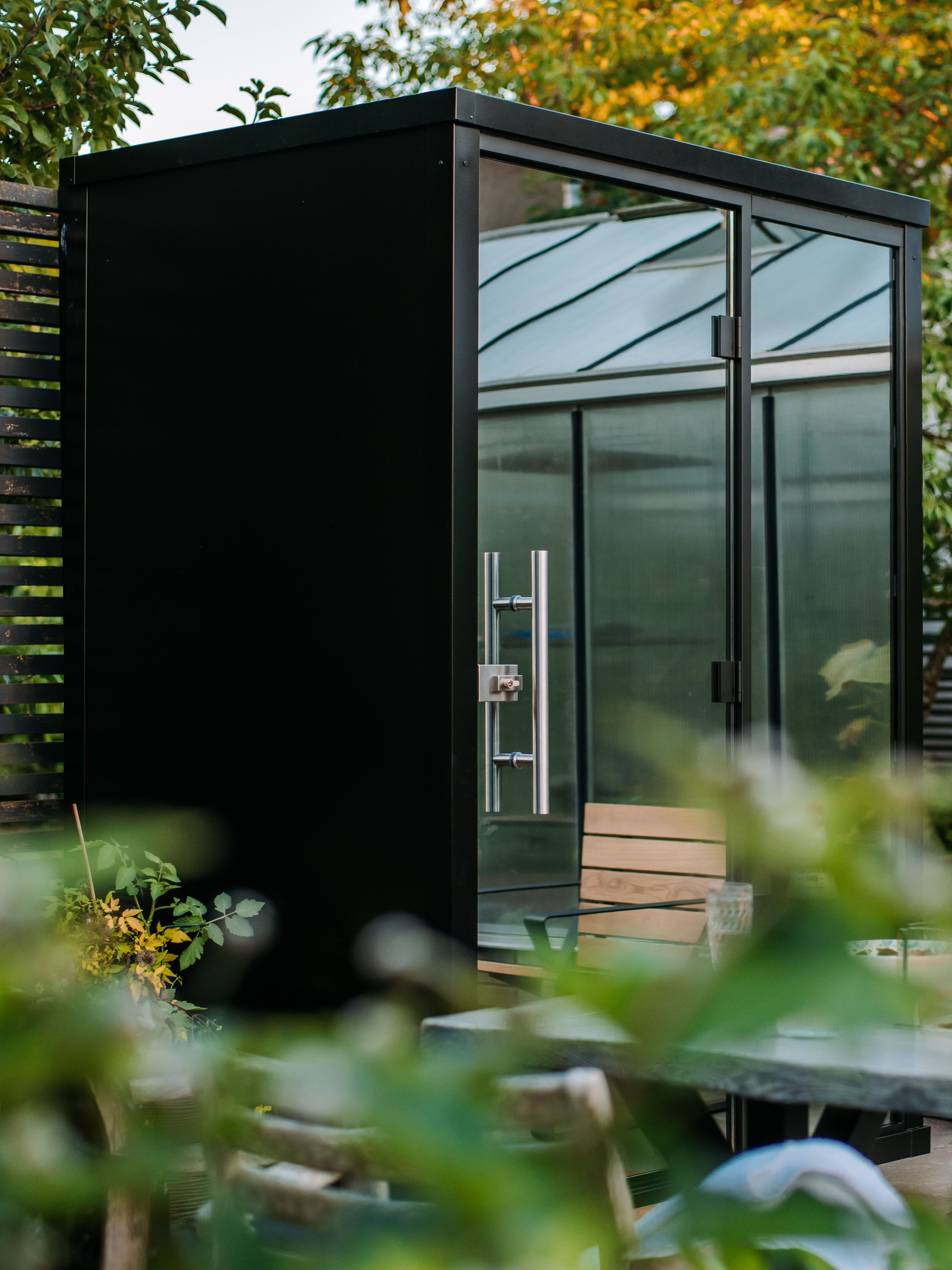 Modern black shed with glass doors in a garden setting