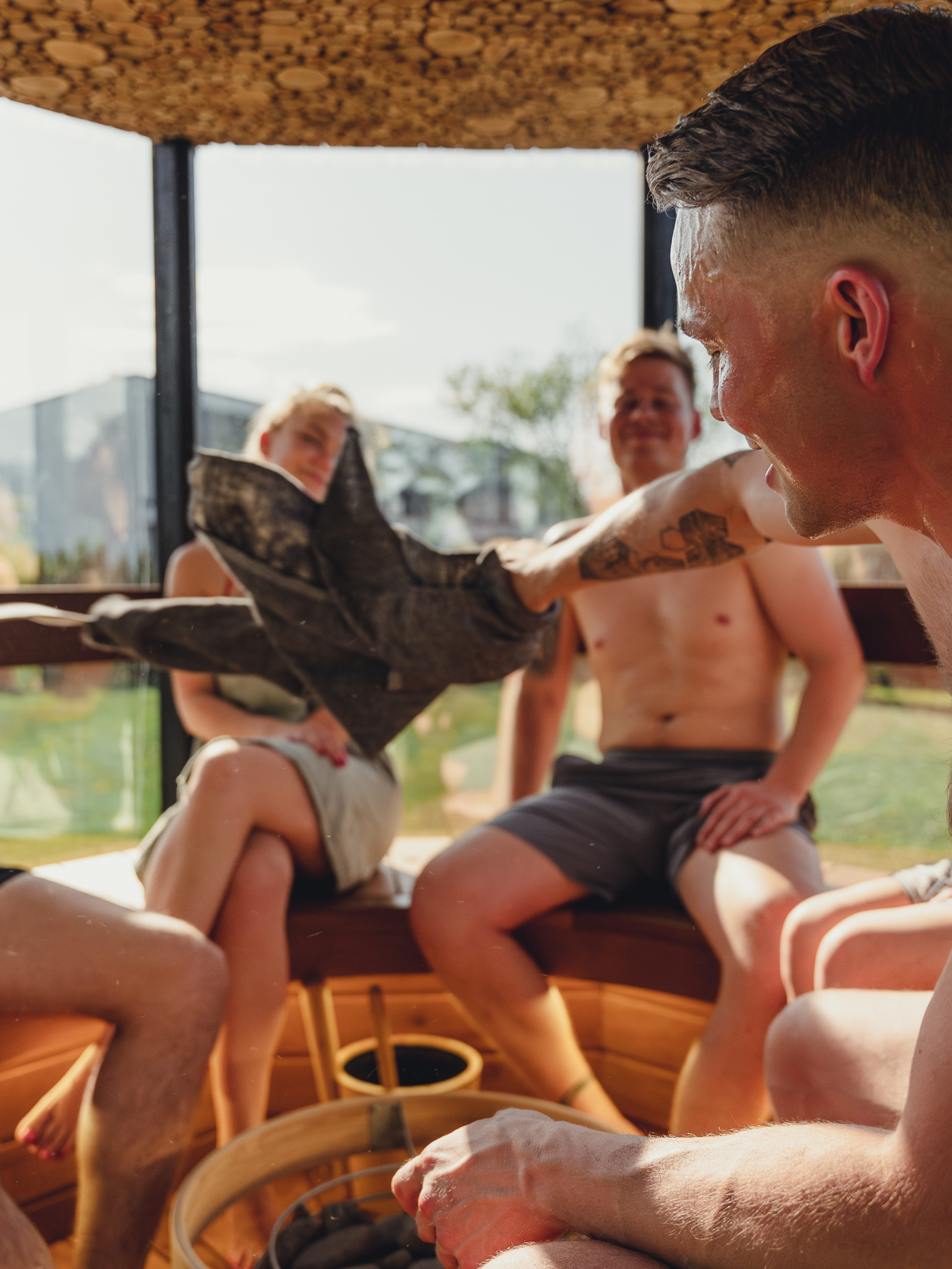 Group of people sitting together in a casual setting with a view of buildings outside.