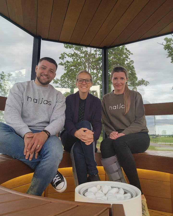 Three people sitting together in a modern outdoor setting with 'haljas' branding.