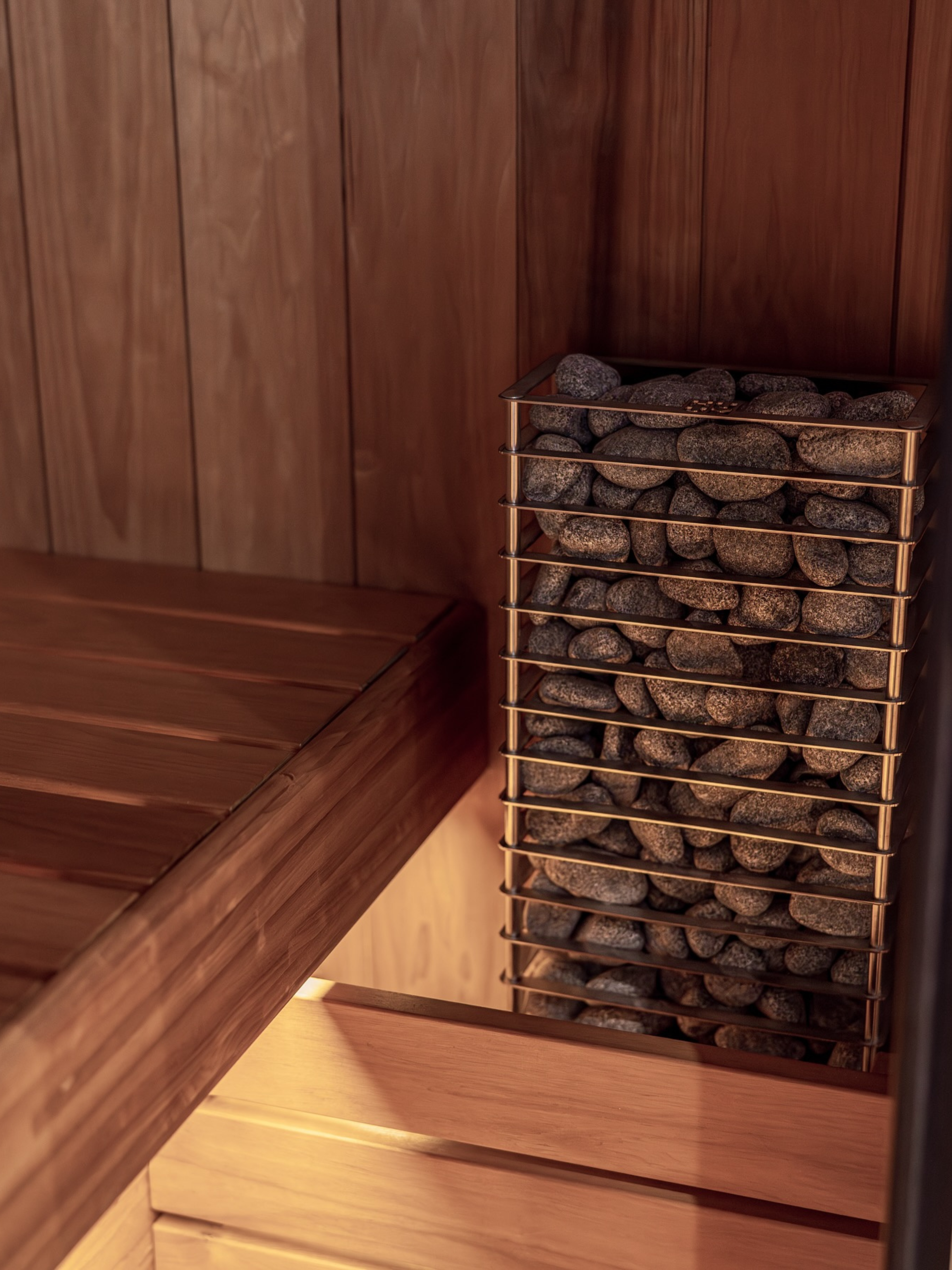 Wooden sauna with a metal basket of stones