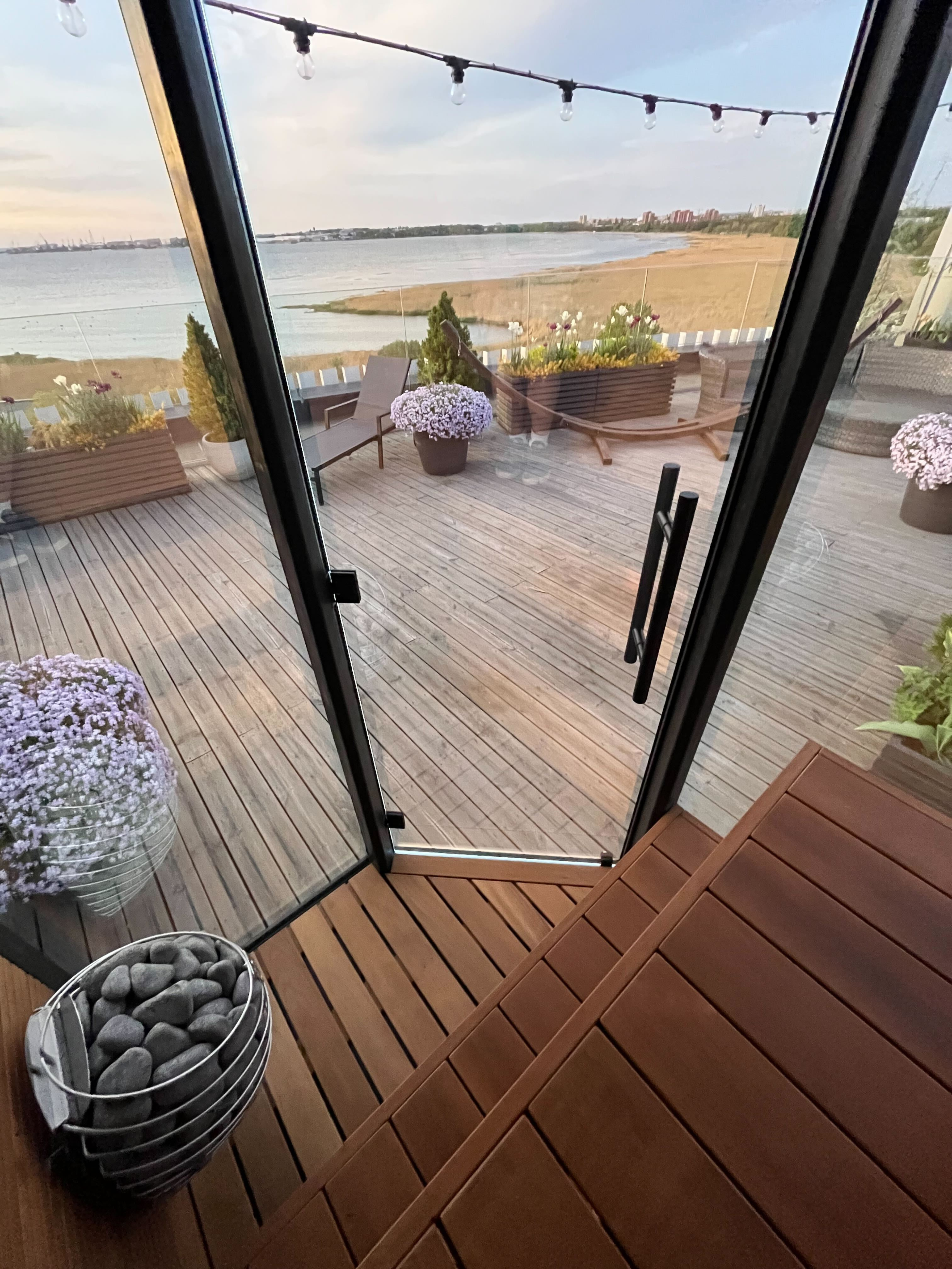 Outdoor deck with a view of a lake, chairs, and plants.