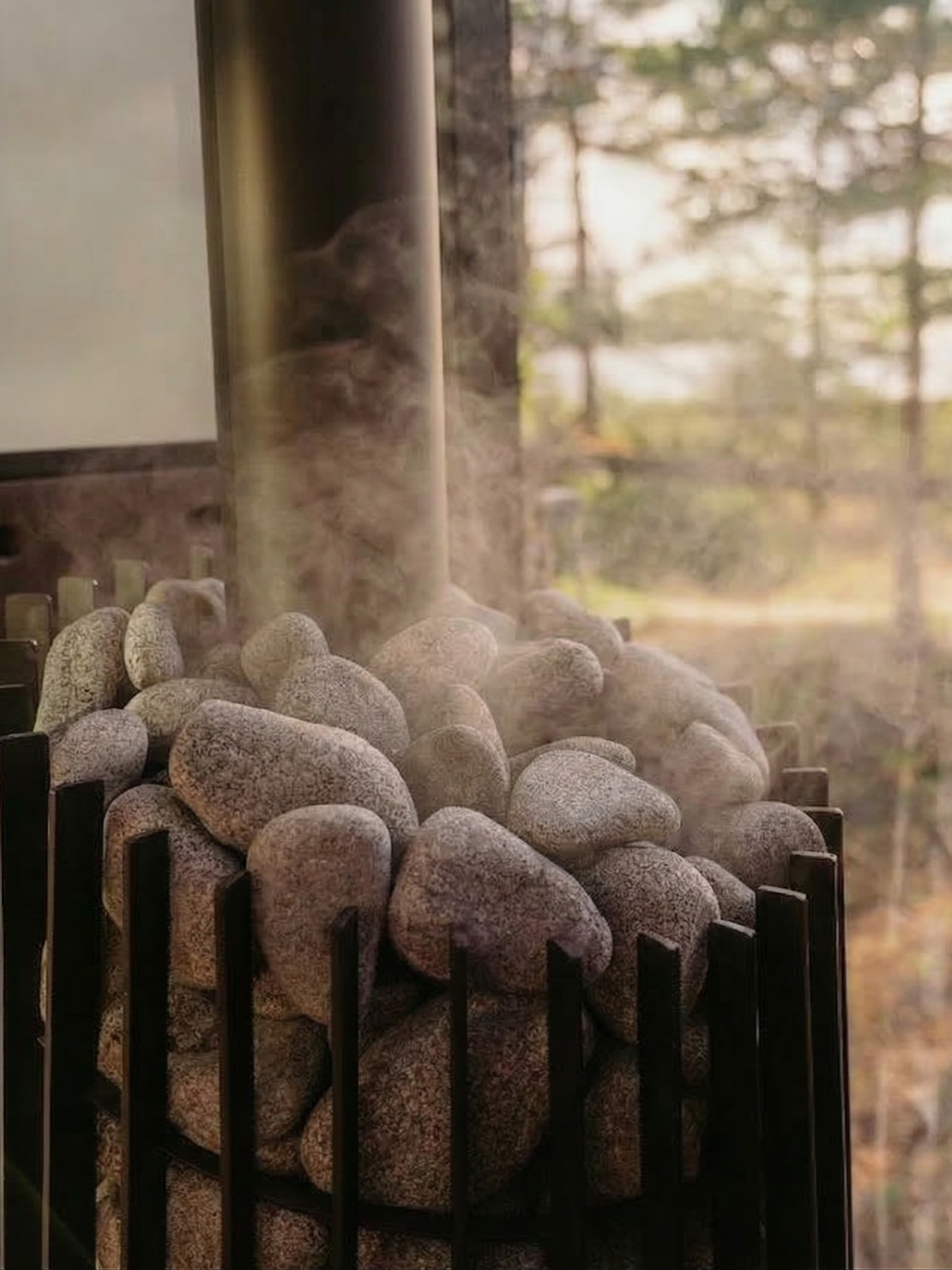 Stacked stones in a fireplace with smoke rising against a forest background