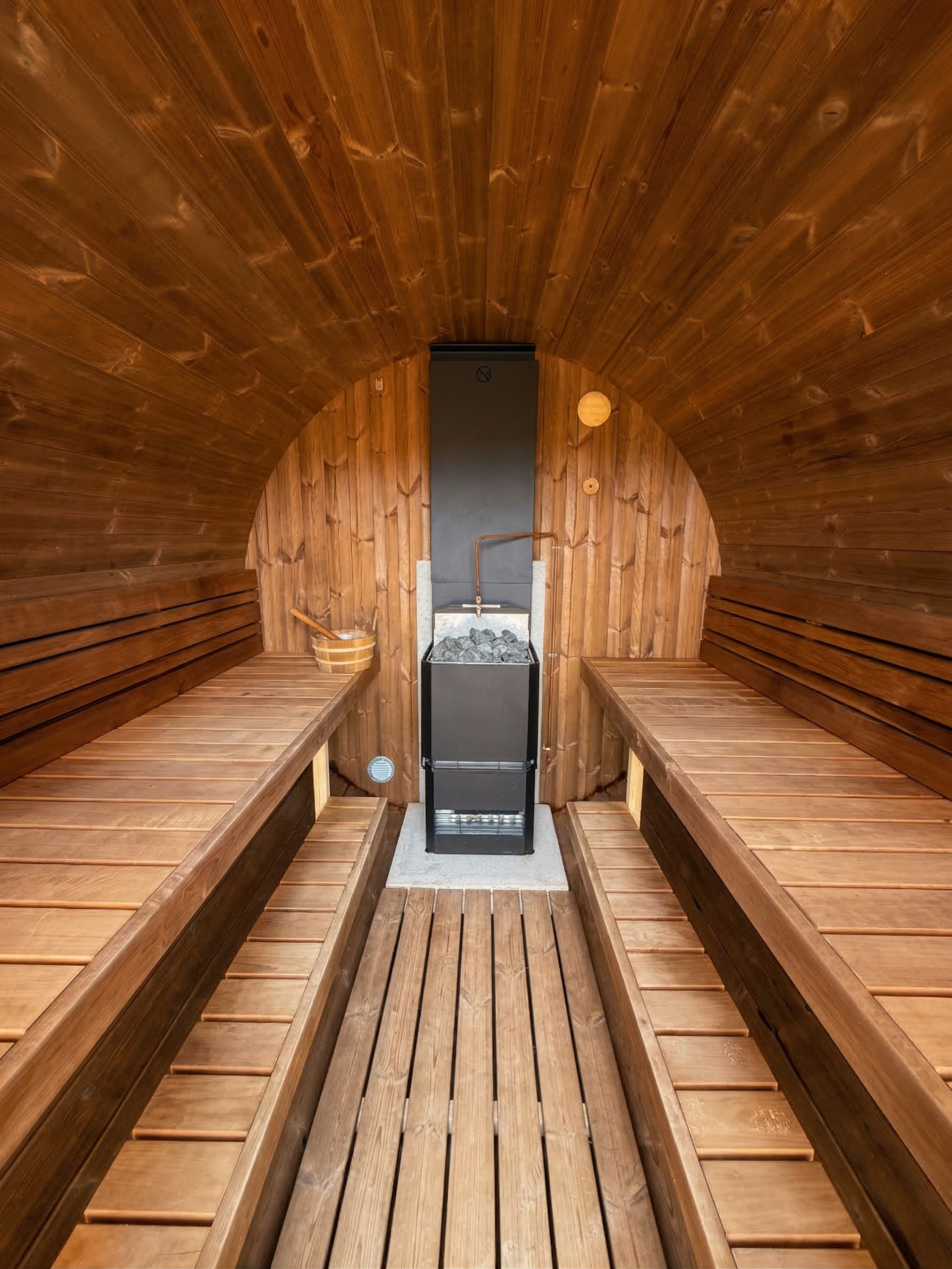 Wooden sauna interior with benches and a stove.