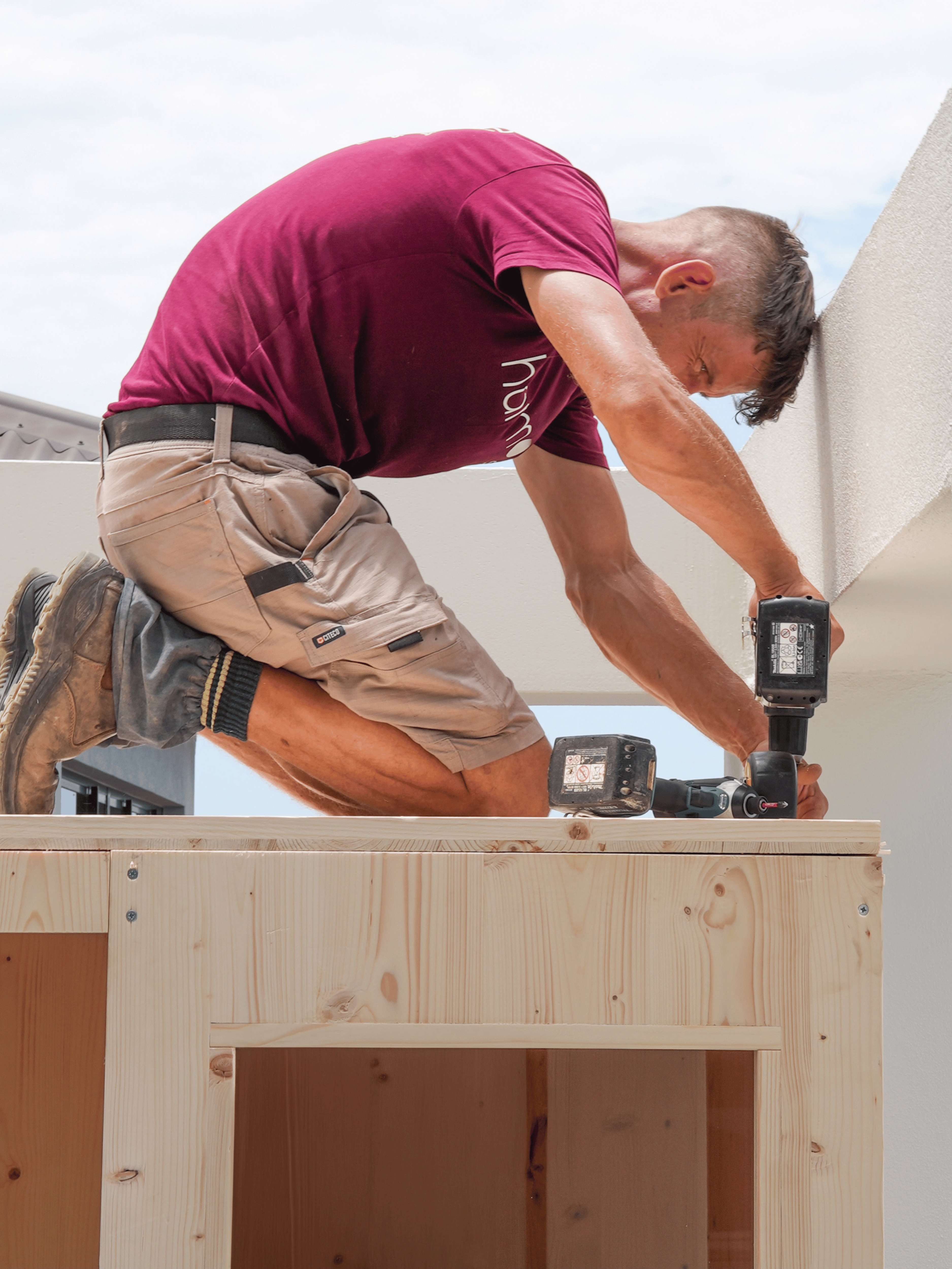Person using a drill on a wooden structure outdoors
