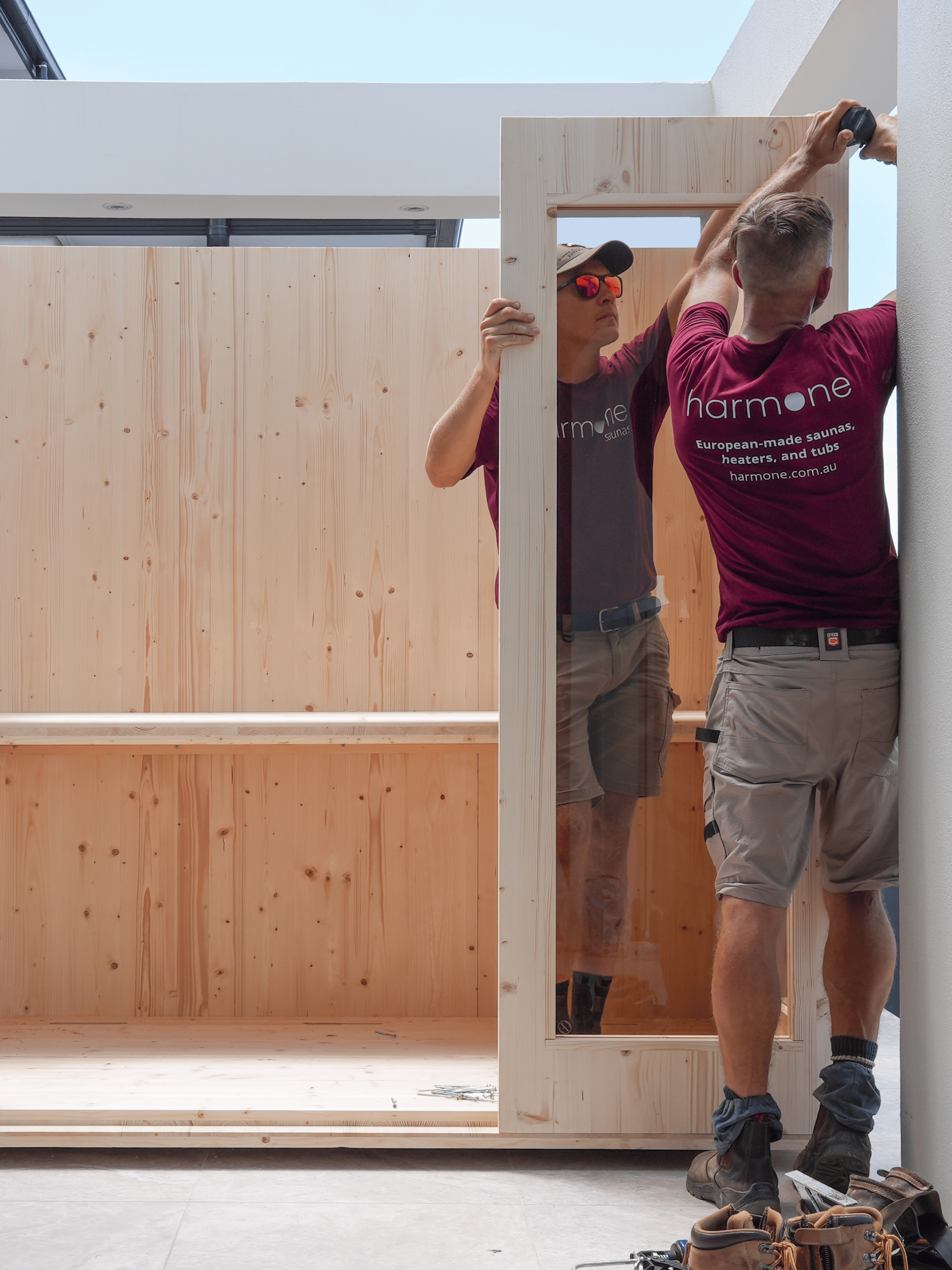 Two men working on a wooden frame inside a building.