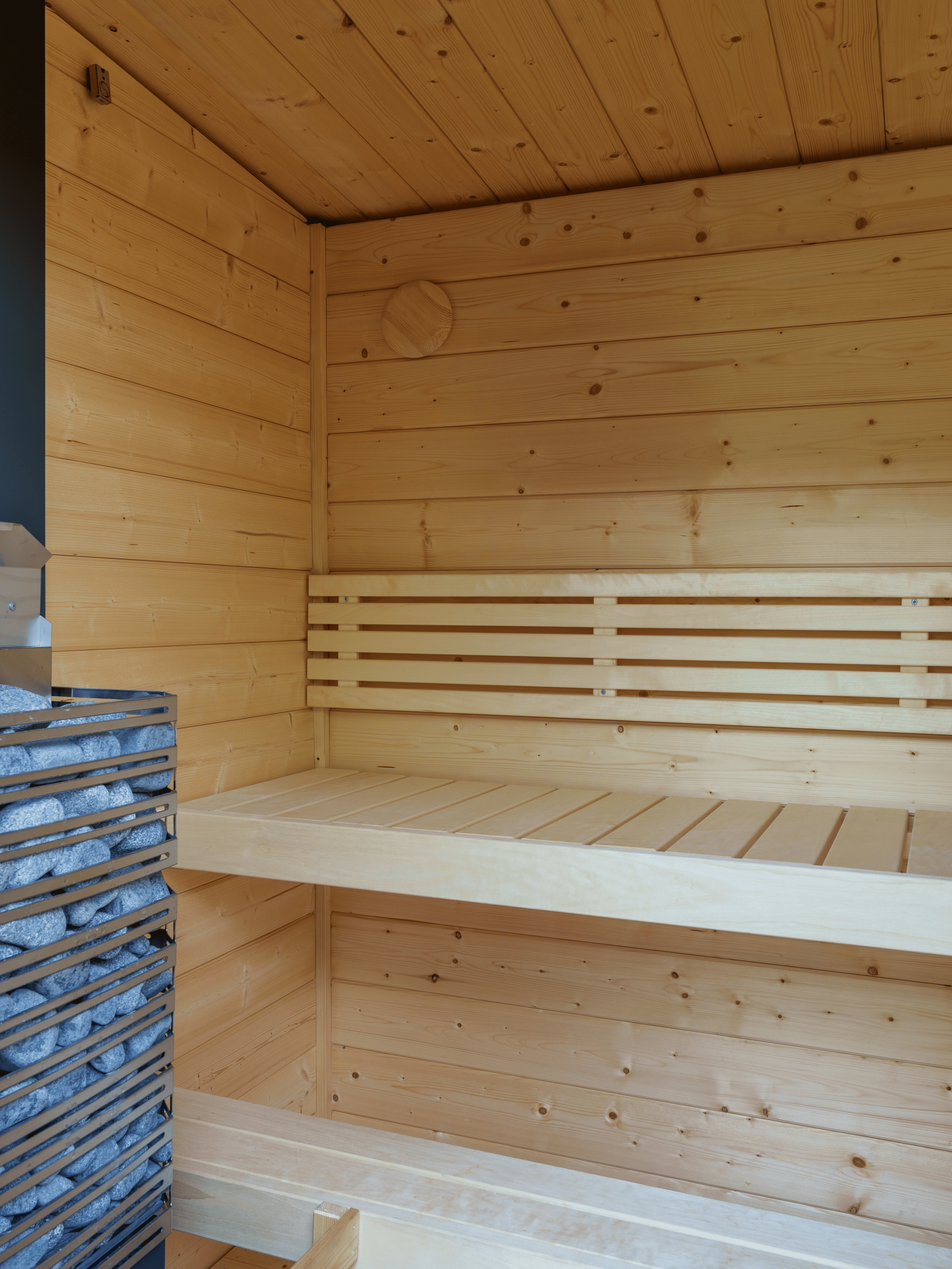 Wooden sauna interior with a bench and stone shelf.