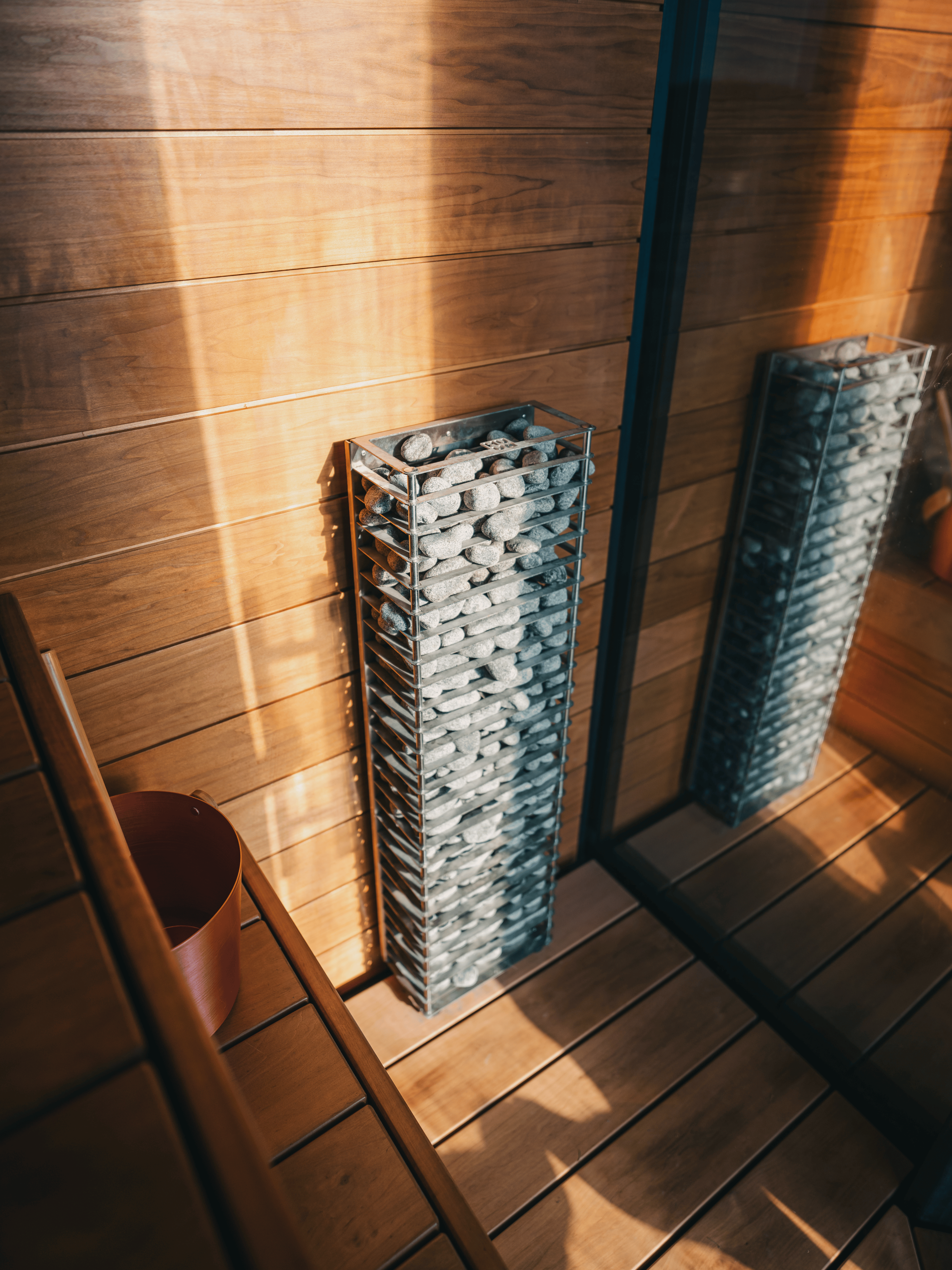 Two tall glass vases filled with pebbles against a wooden wall.