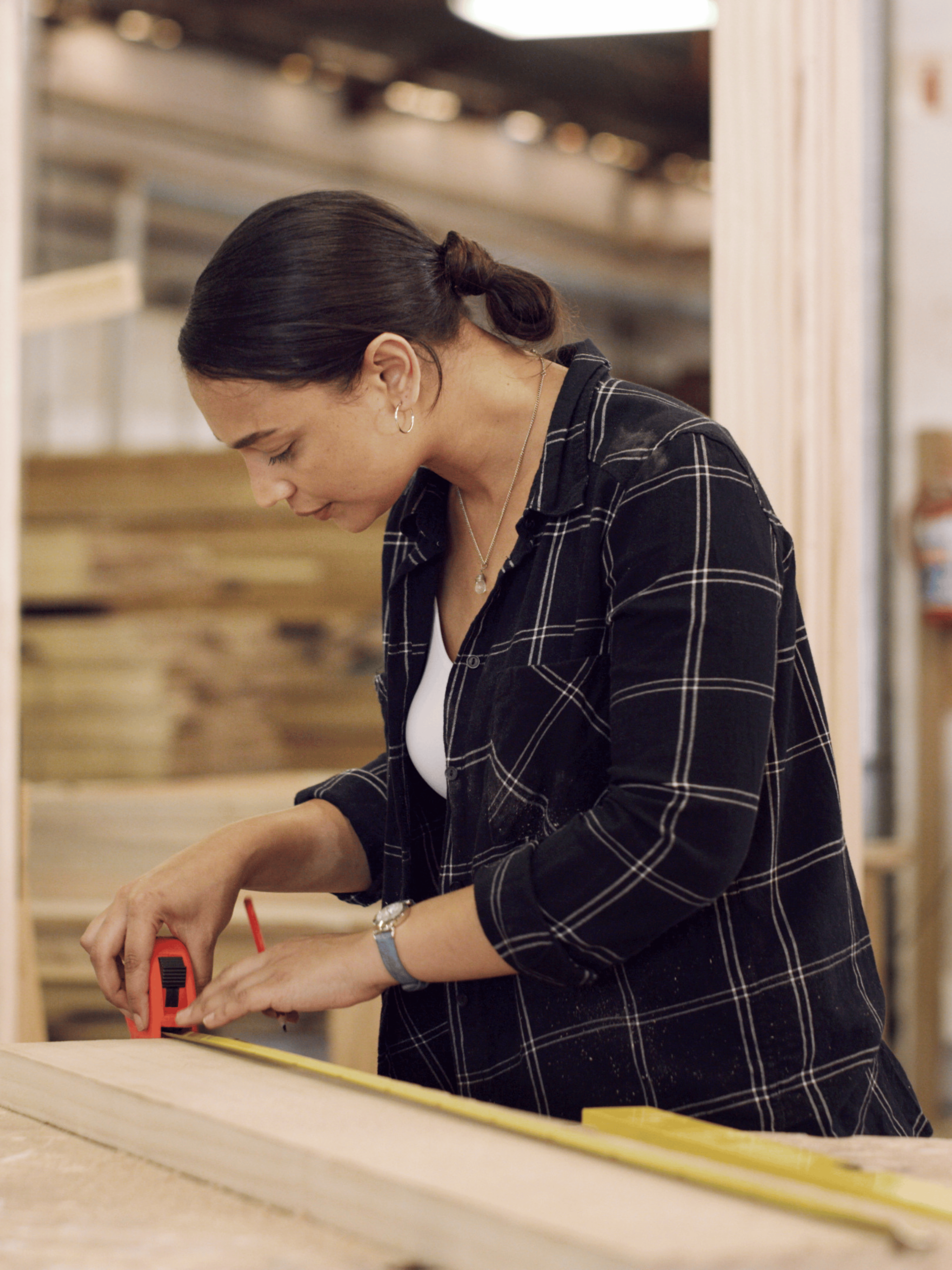 Woman measuring wood in a workshop setting