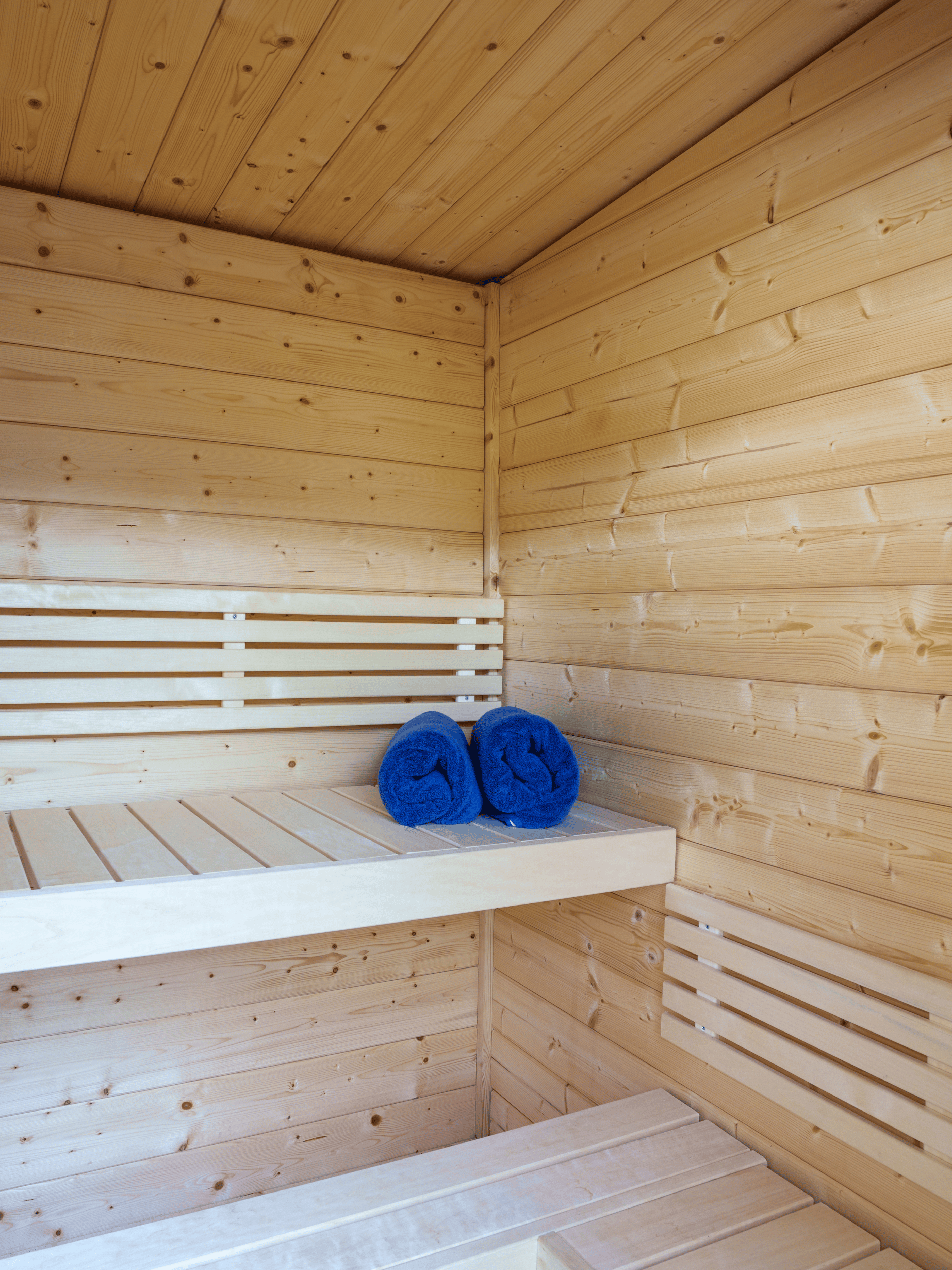 Wooden sauna with a bench and blue towels