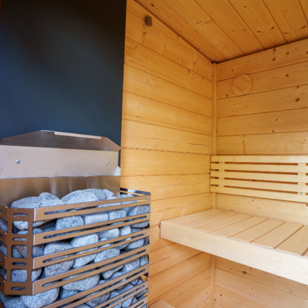 Wooden sauna with a shelf and stone basket against a dark wall