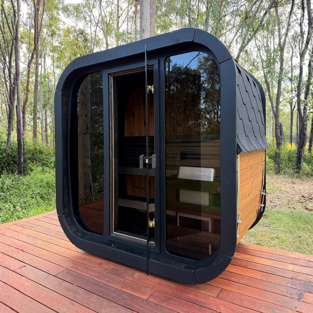 Portable cabin with black frame and glass doors on a wooden deck in a forest setting