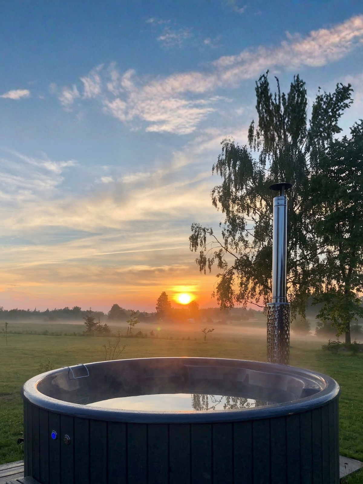 Hot tub in a field with a sunset in the background